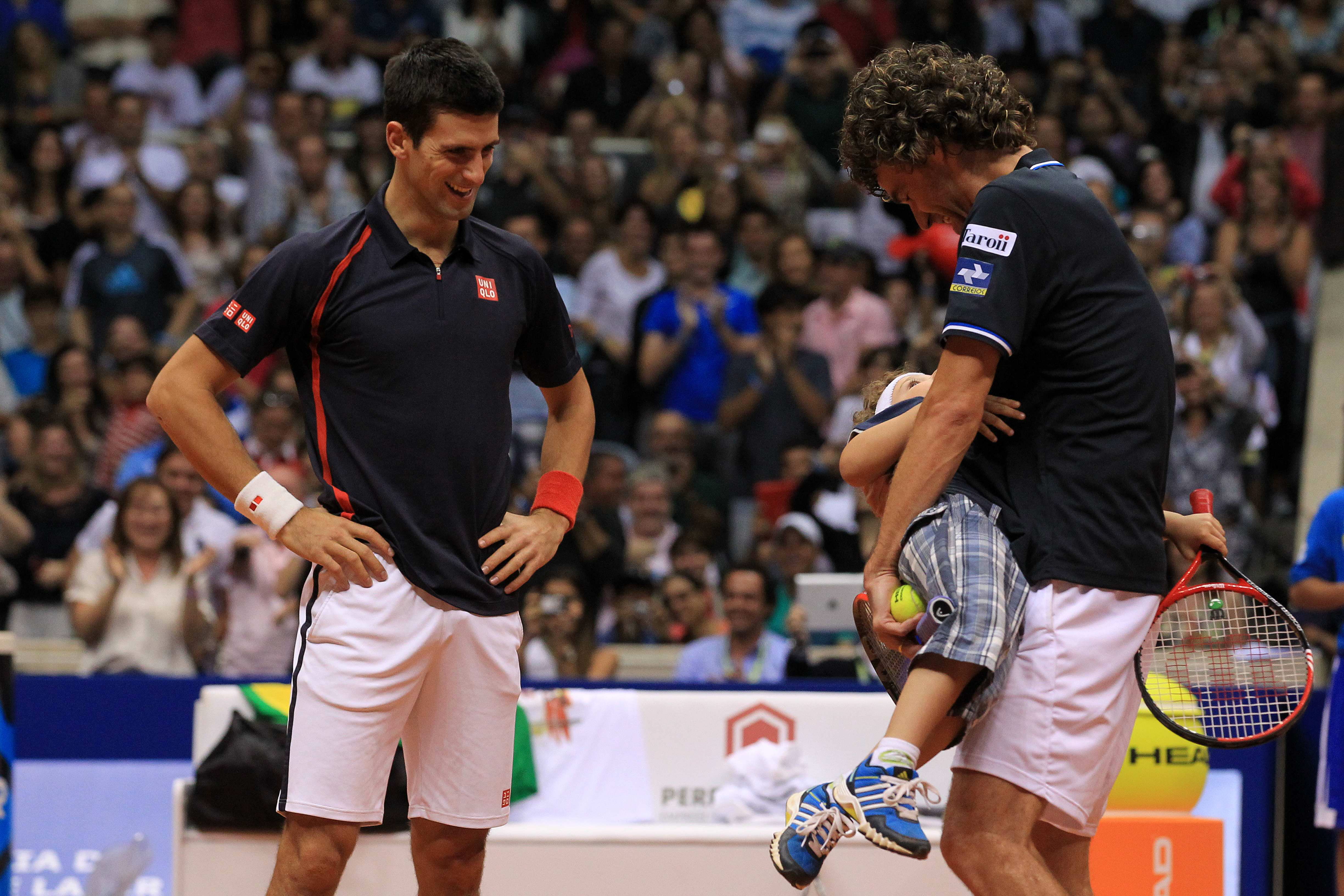 epa03475783 Brazilian former tennis player Gustavo Kuerten (R) carry a kid from the public next to Serbian Novak Djokovic (L) during an exhibition game at Maracanazinho colliseum in Rio de Janeiro, Brazil, 17 November 2012.  EPA/Marcelo Sayao