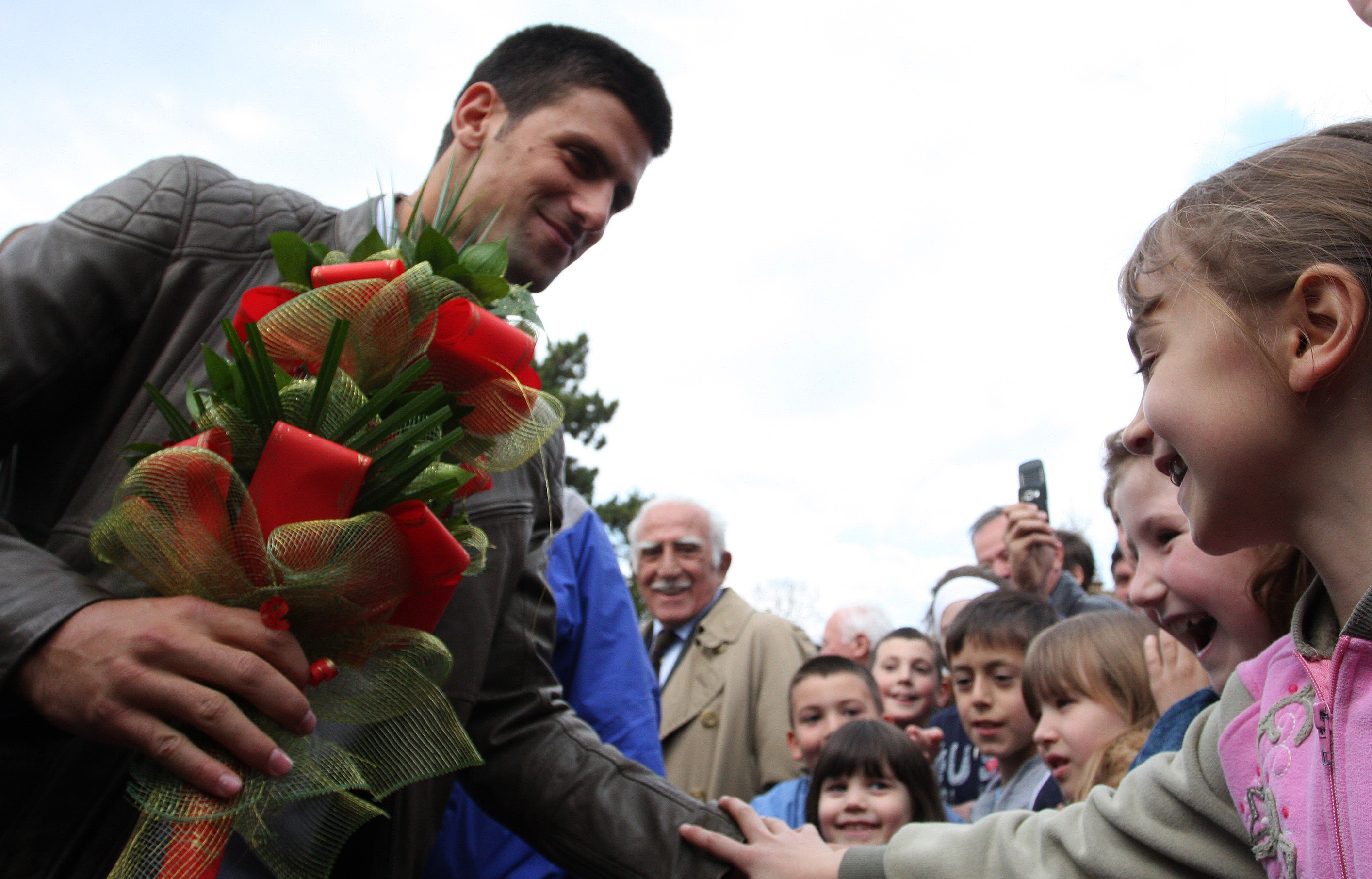 Tennis player Novak Djokovic receives flowers as he is welcomed in the ethnically divided city of Mitrovica