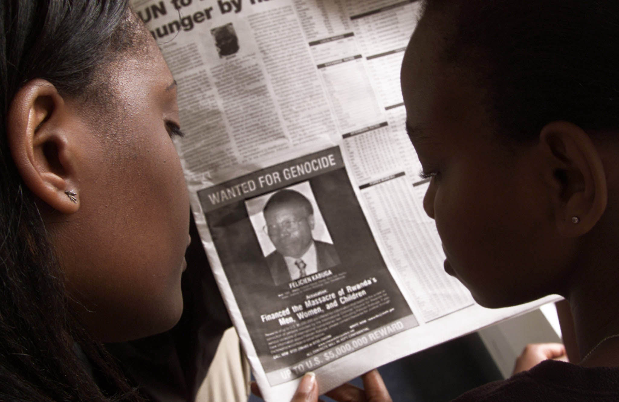 READERS LOOK AT A PICTURE OF A RWANDAN WANTED FOR THE ALLEGEDMASTERMIND OF RWANDA'S 1994 GENOCIDE.