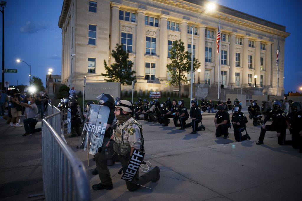 Officers and protesters take a knee in front of the Des Moines Police Station in an act of solidarity on Sunday, May 31, 2020 in Des Moines. The protest was peacefully dispersed shortly thereafter. (Brian Powers/The Des Moines Register via AP)