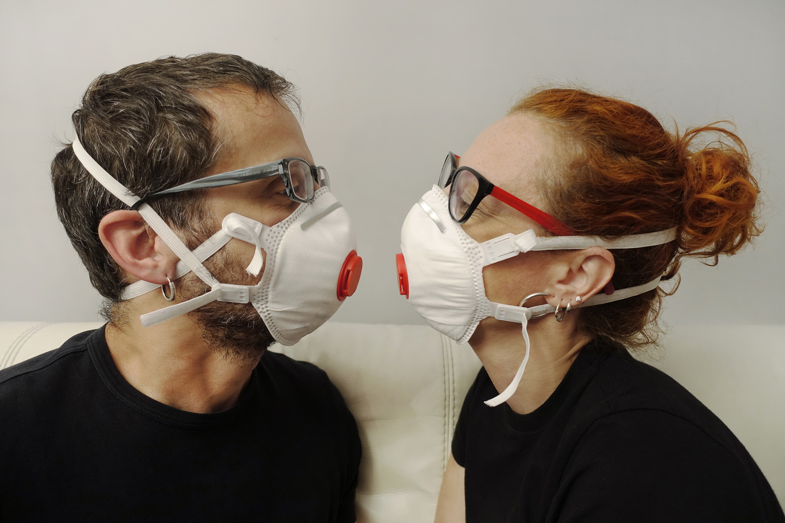 Casual charming couple with glasses wearing anti virus filter masks, keeping a social distance, close up. Quarantine concept, corona virus time.