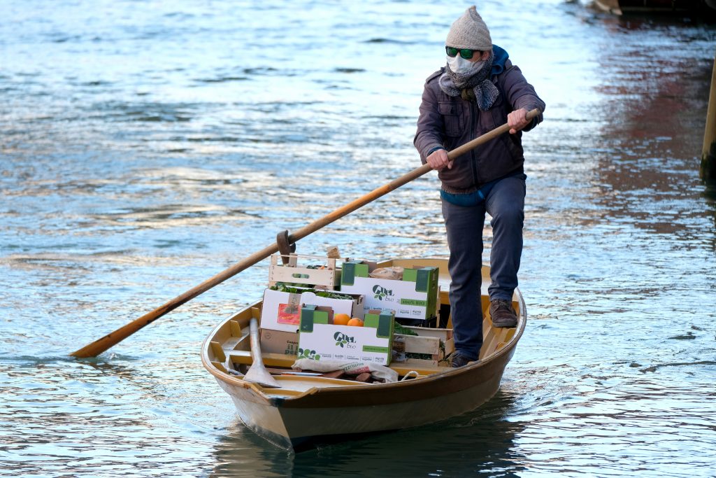 A man delivers fruits and vegetables by rowboat to his customers' houses during the current emergency of the coronavirus disease (COVID-19) in Venice, Italy, March 25, 2020. REUTERS/Manuel Silvestri - RC21RF9B2UHP