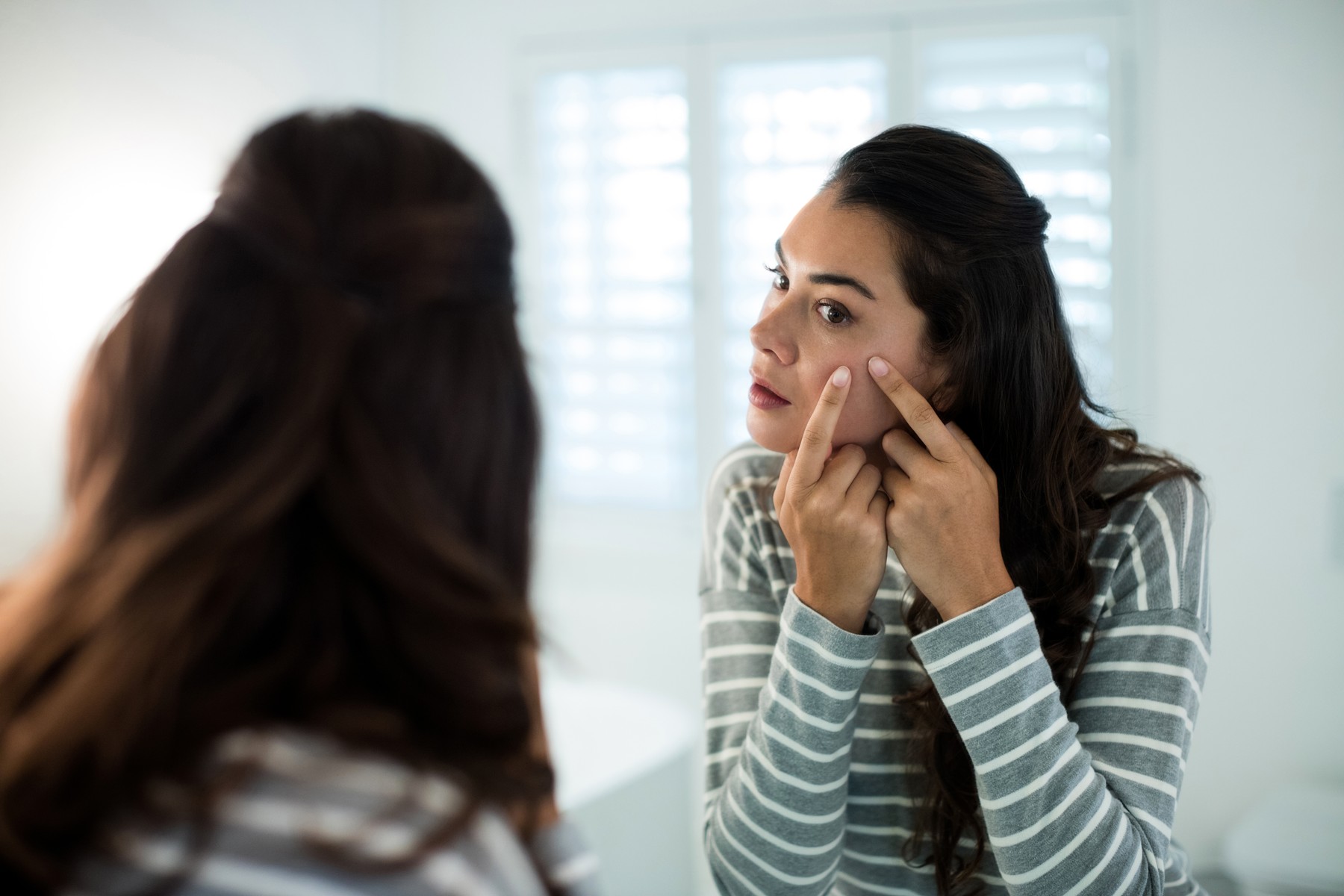 Woman squeezing pimples in front of bathroom mirror at home, Image: 326969689, License: Rights-managed, Restrictions: , Model Release: yes, Credit line: - / Wavebreak / Profimedia