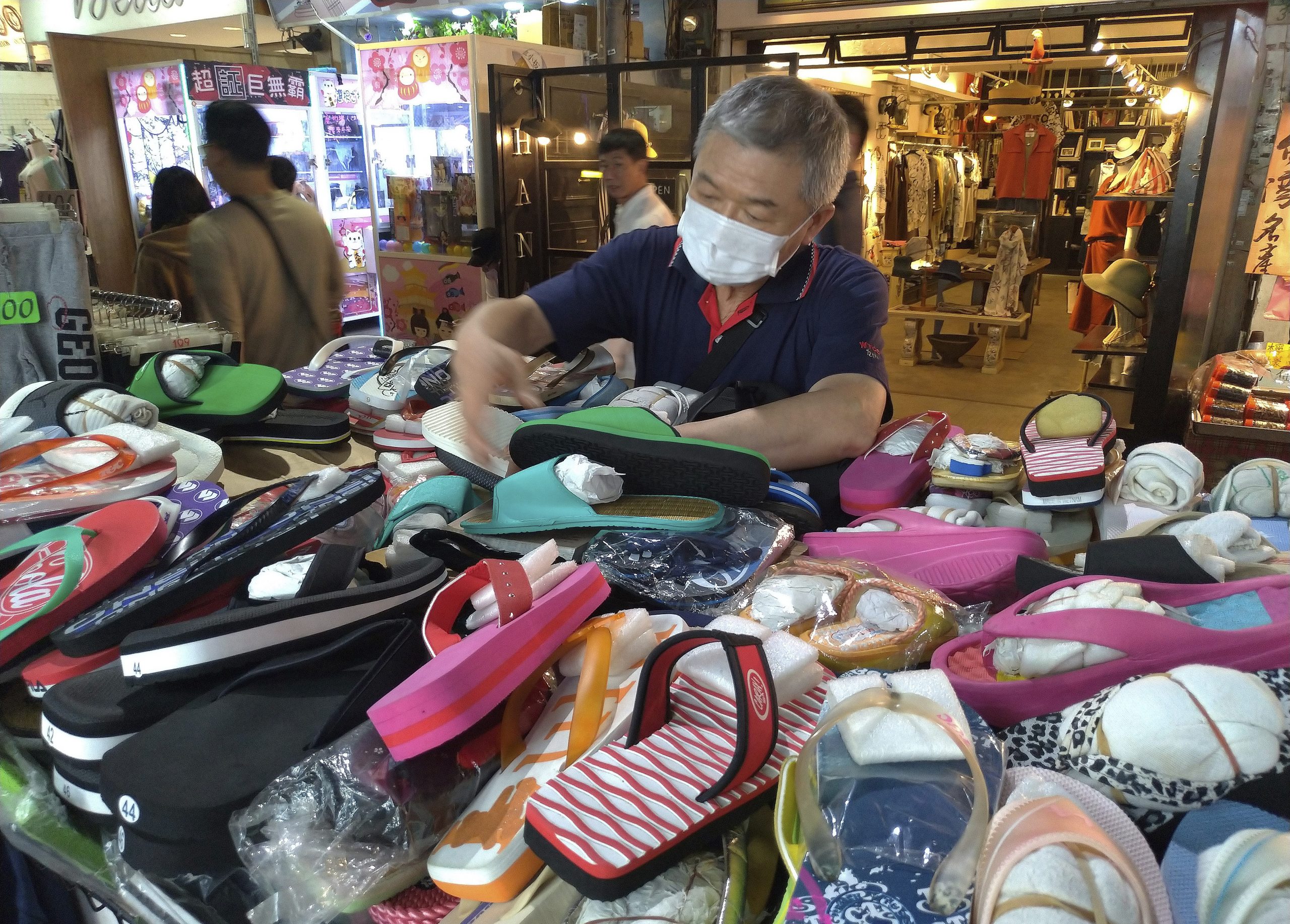 A vendor wears a face mask to protect against the spread of the coronavirus and waits for customers at a night market in Taipei, Taiwan, Thursday, March 26, 2020. (AP Photo/Chiang Ying-ying)