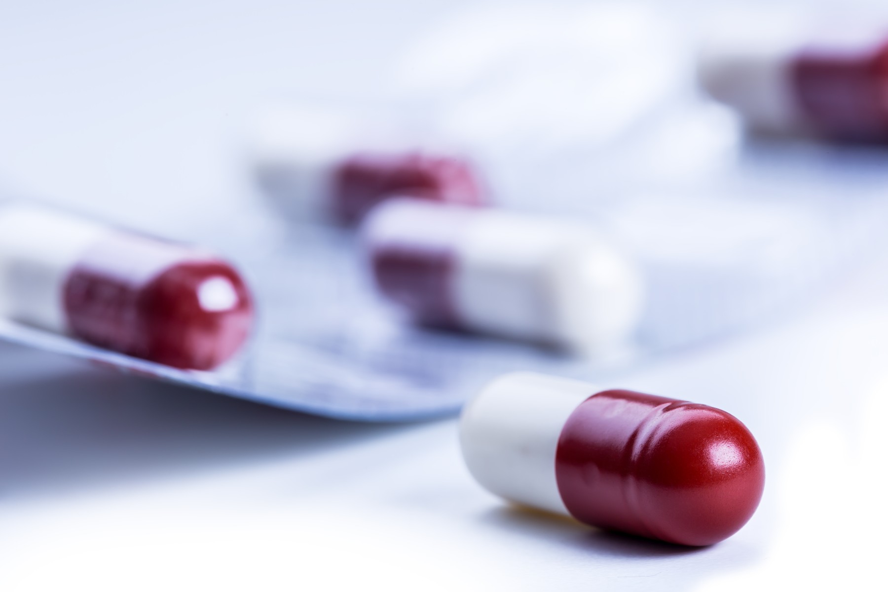 Pills. Tablets. Capsule. Heap of pills. Medical background. Close-up of pile of red white tablets - capsule. Pills and tablets.Blue background