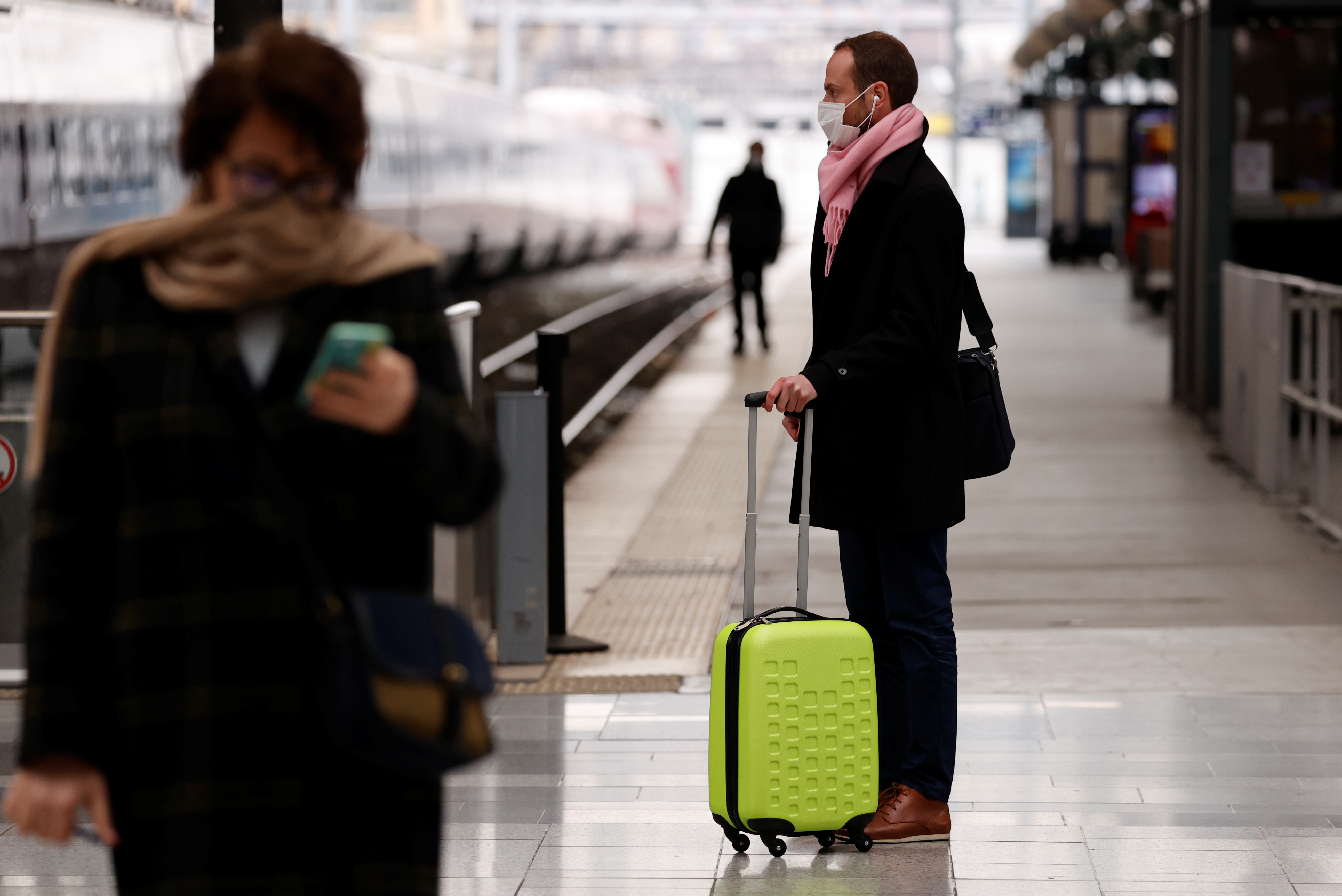A man wearing a protective face mask waits for a train at Gare du Nord railway station in Paris