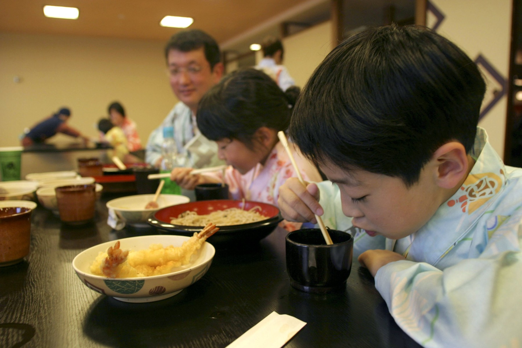 A Japanese family eating noodles and other foods with chopsticks in a restaurant at the Oedo Onsen Monogatari a 24 hour onsen hot spring bath resort in Odaiba, Tokyo, Japan,Image: 4420890, License: Rights-managed, Restrictions: , Model Release: no