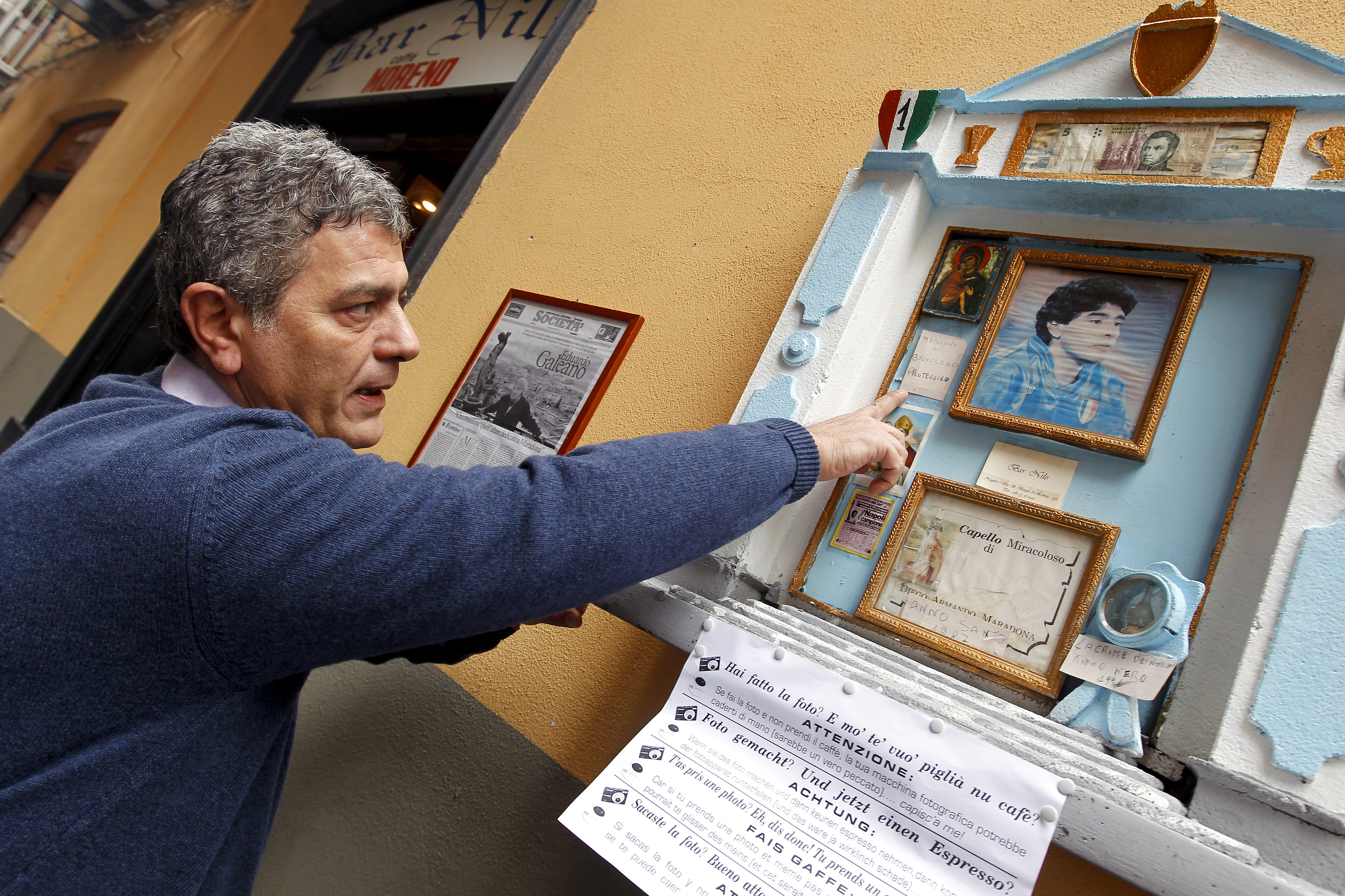 Nilo bar owner Carmine Alcide points to a small altar containing hair believed to belong to former Argentina international and Napoli soccer player Diego Armando Maradona in Naples