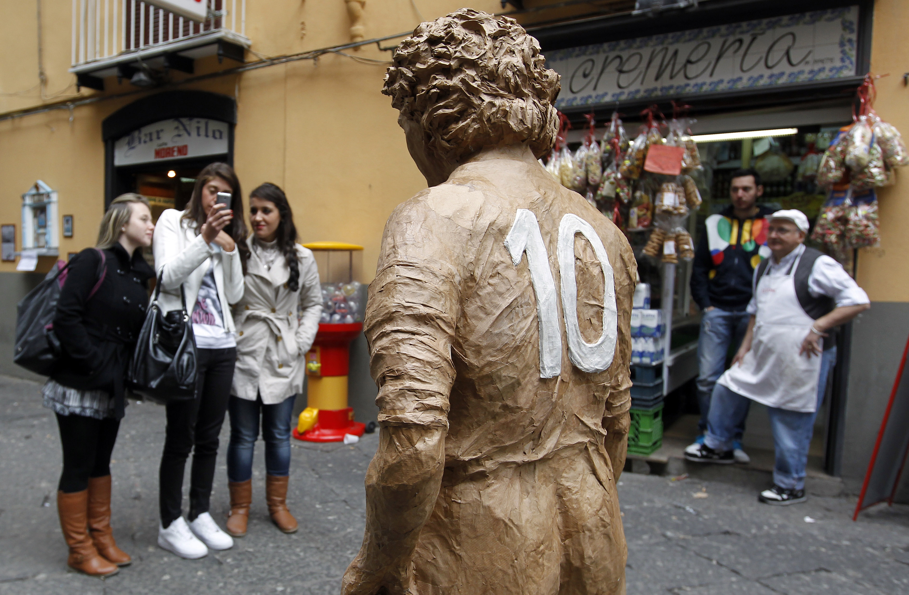 A girl take a picture of Argentina's soccer star Diego Armando Maradona paper-mache statue in Naples