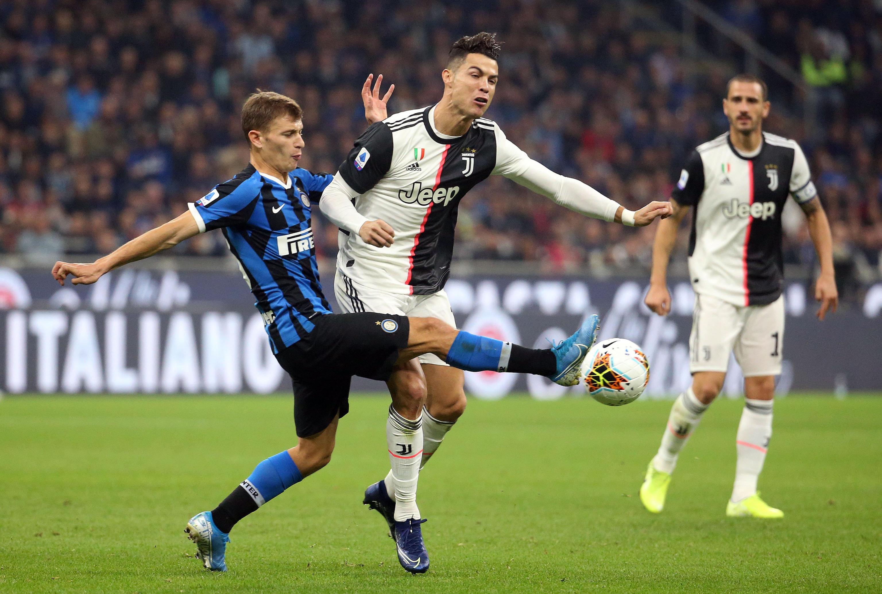 epa07902301 Inter's Nicolo Barella (L) challenges for the ball with Juventus' Cristiano Ronaldo (C) during the Italian serie A soccer match between FC Inter and Juventus FC at Giuseppe Meazza stadium in Milan, Italy, 6 October 2019.  EPA-EFE/MATTEO BAZZI