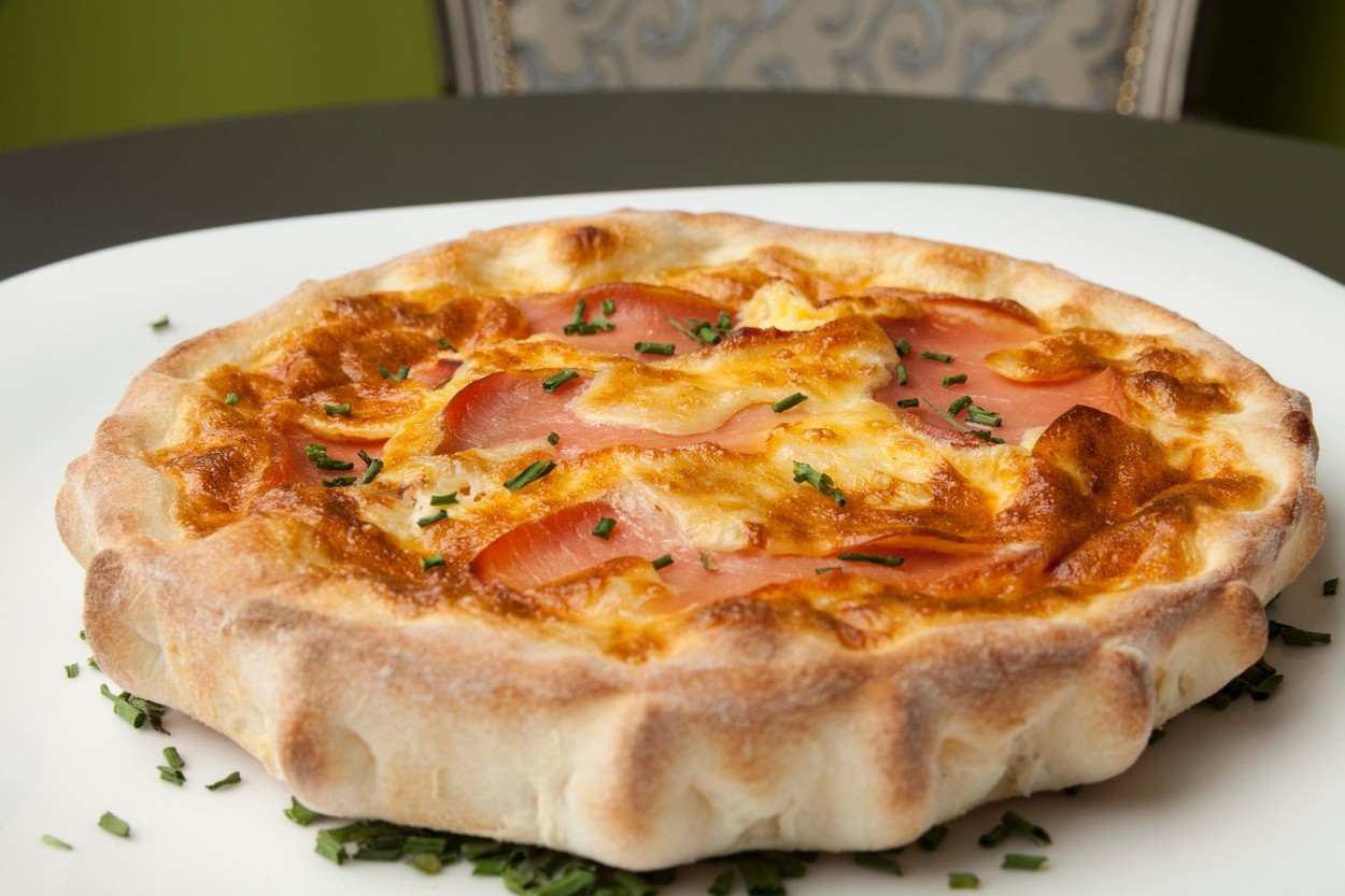 baked bun with ham and eggs on white plate