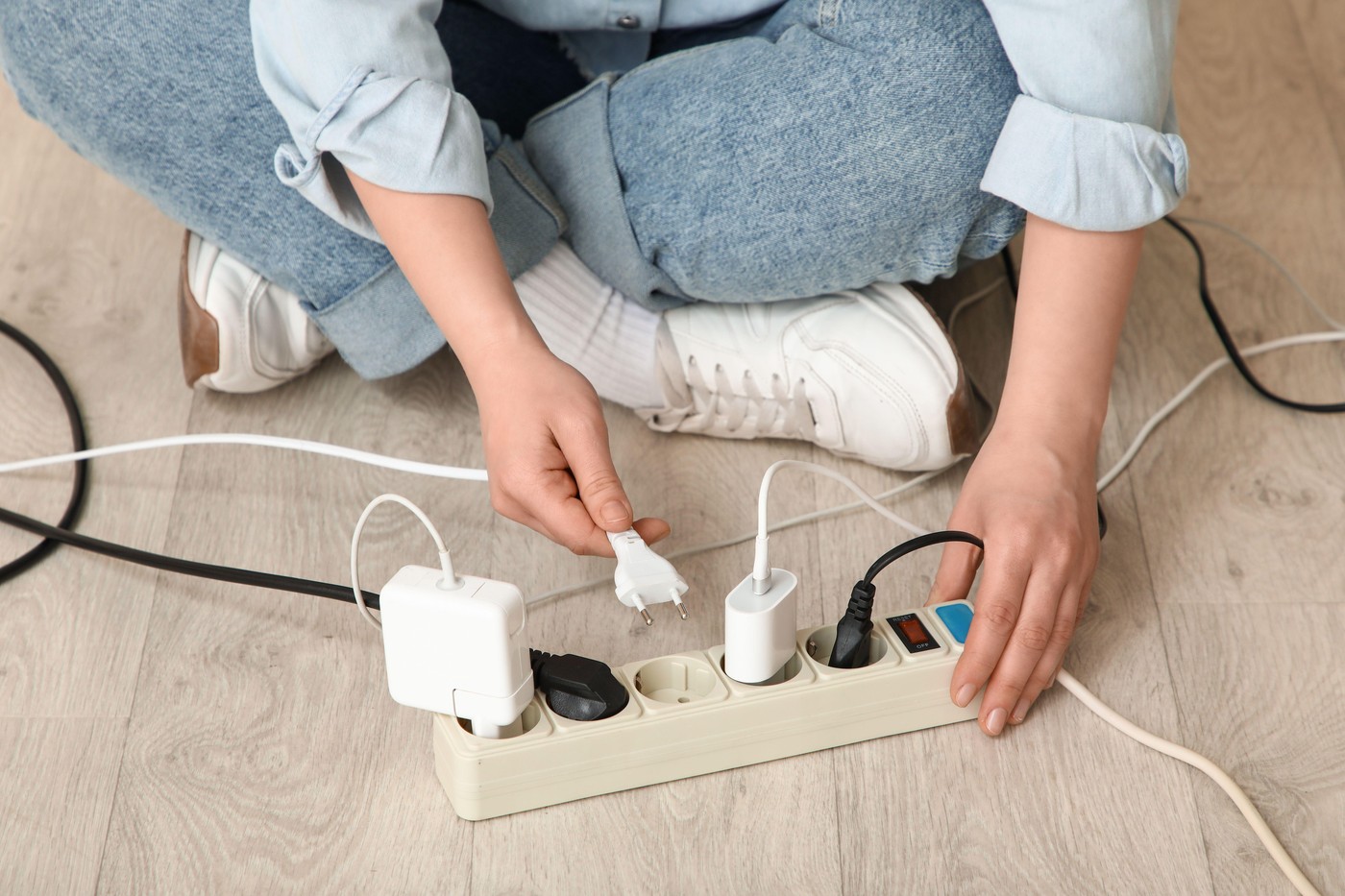 Woman getting out plug from extension cord on floor at home, closeup
