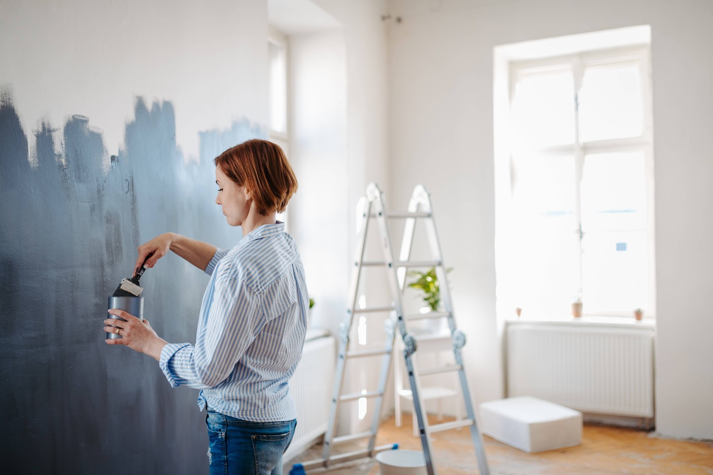 Beautiful woman painting walls of her new apartment by herself.