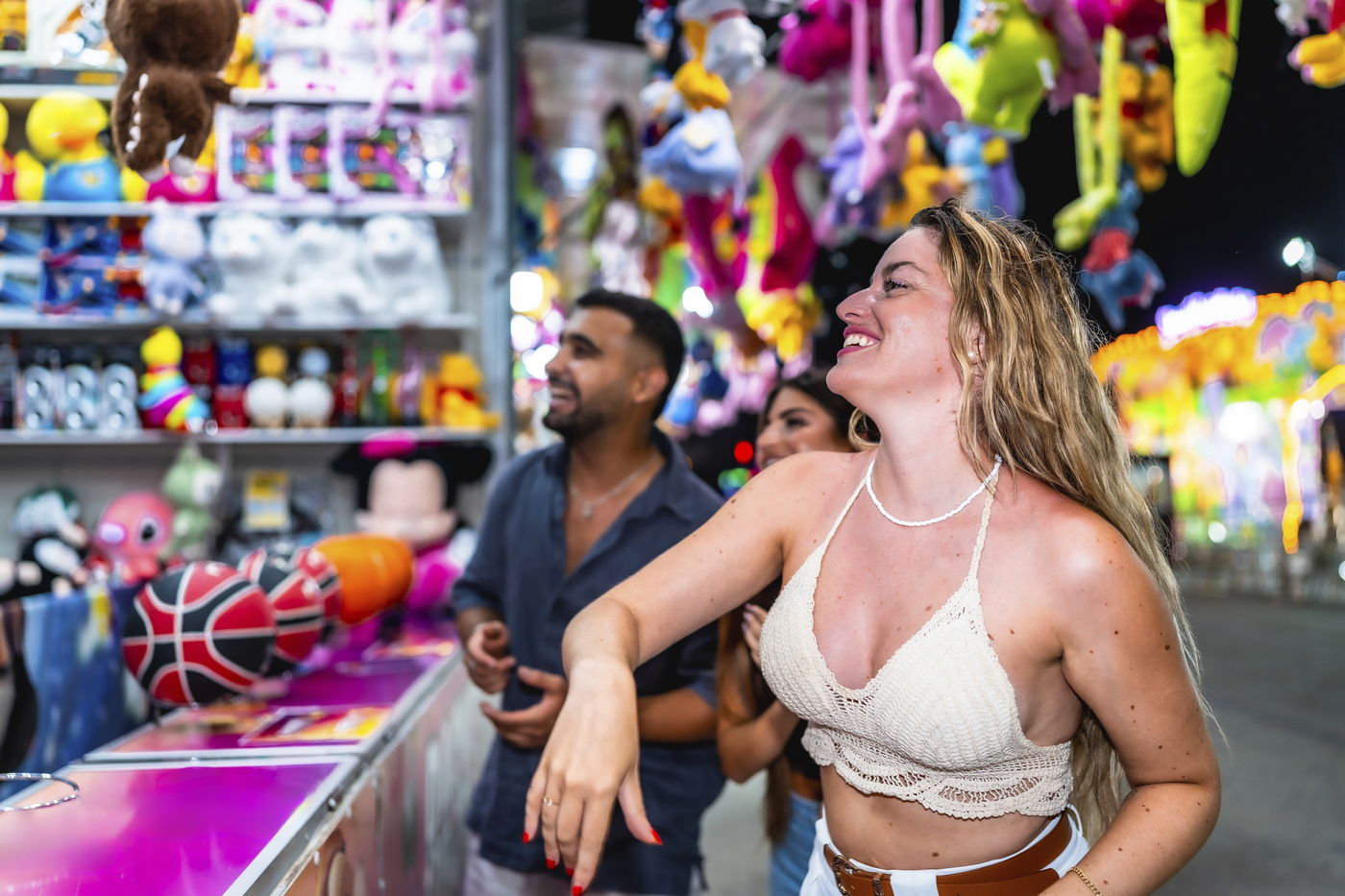 Happy friends playing at a throwing game stall trying to win plush toys at amusement park at night,Image: 1027760263, License: Royalty-free, Restrictions: , Model Release: yes, Credit line: Unai Huizi / imageBROKER / Profimedia