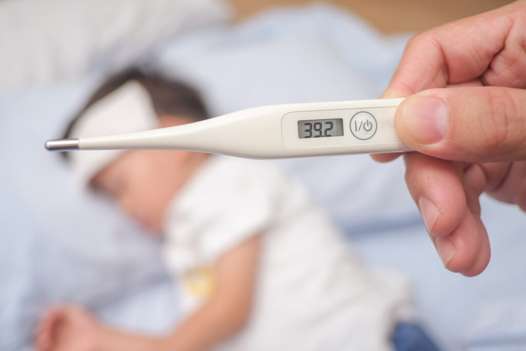 Fever, Close-up medical thermometer, Parent / Father measuring temperature of his ill kid, Asian 3 - 4 years old toddler boy gets high fever lying on bed with cold compress on forehead to cool a fever deca bolest, virusi bakterije