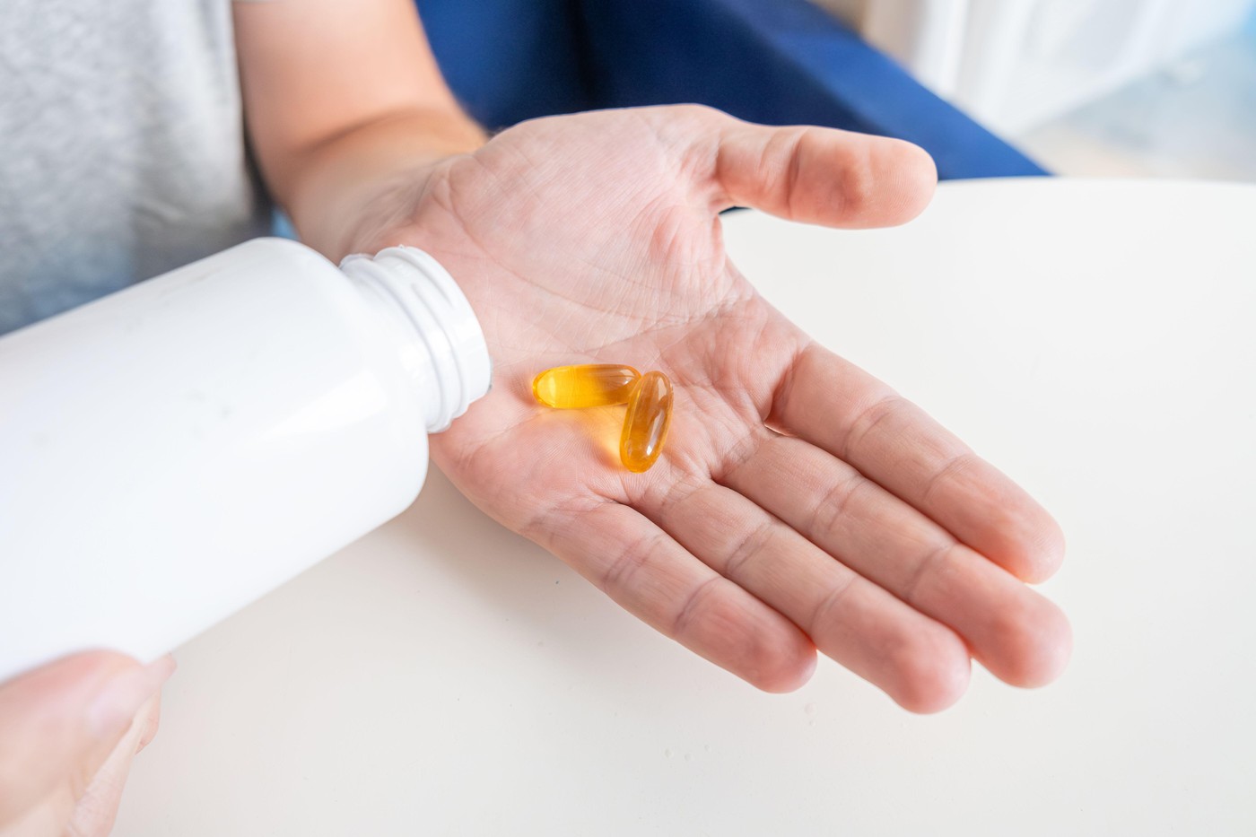 Man pouring fish oil capsules with omega 3, vitamin D in hand from medicine bottle. Nutritional supplement. Health support and treatment concept