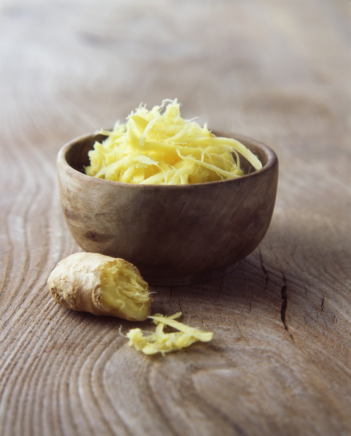Fresh ginger root grated in wooden bowl