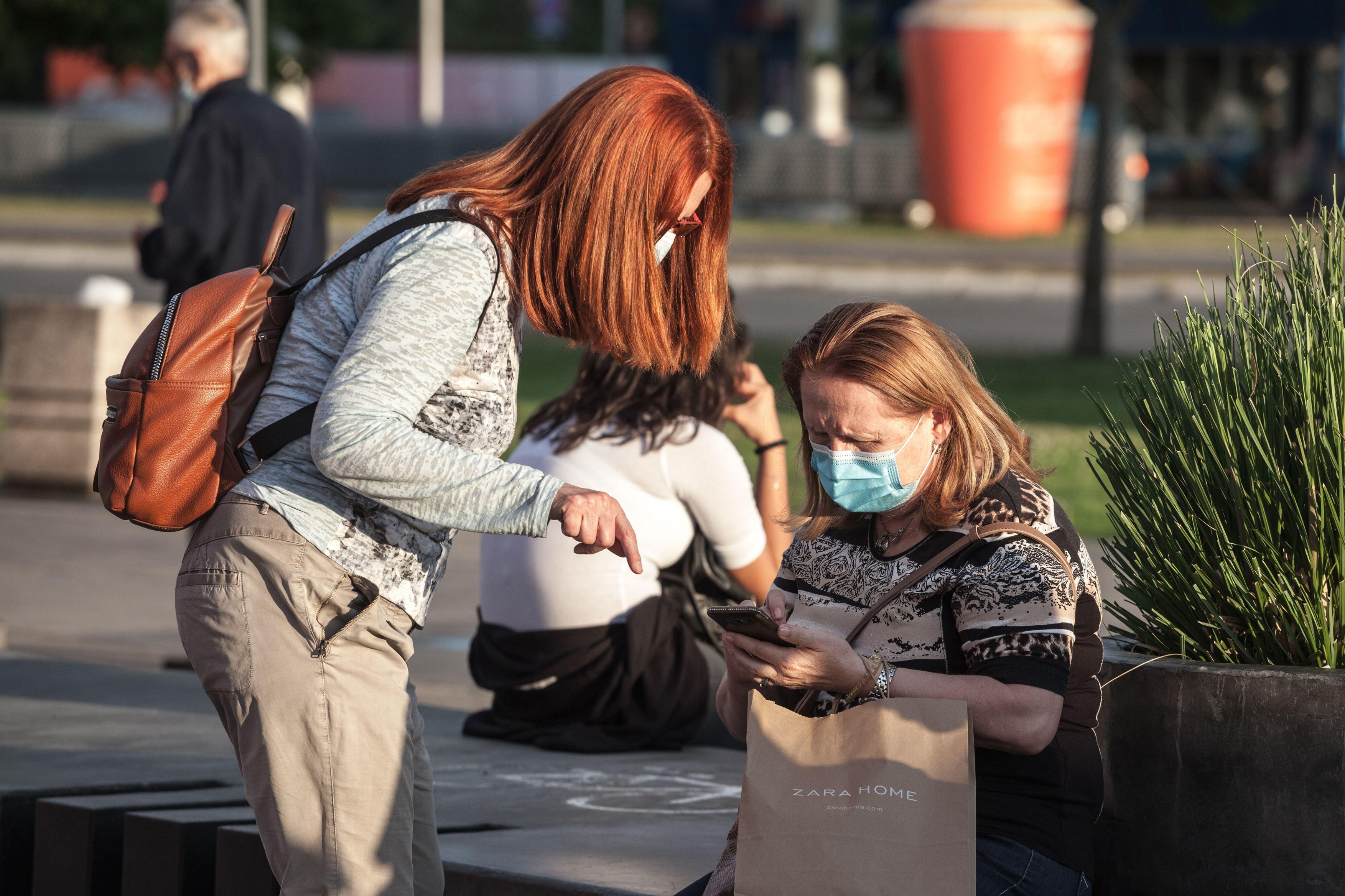 BELGRADE, SERBIA - JULY 19, 2020: Old senior women wearing a respiratory facemask, confused, trying to understand apps on a smartphone during the coro