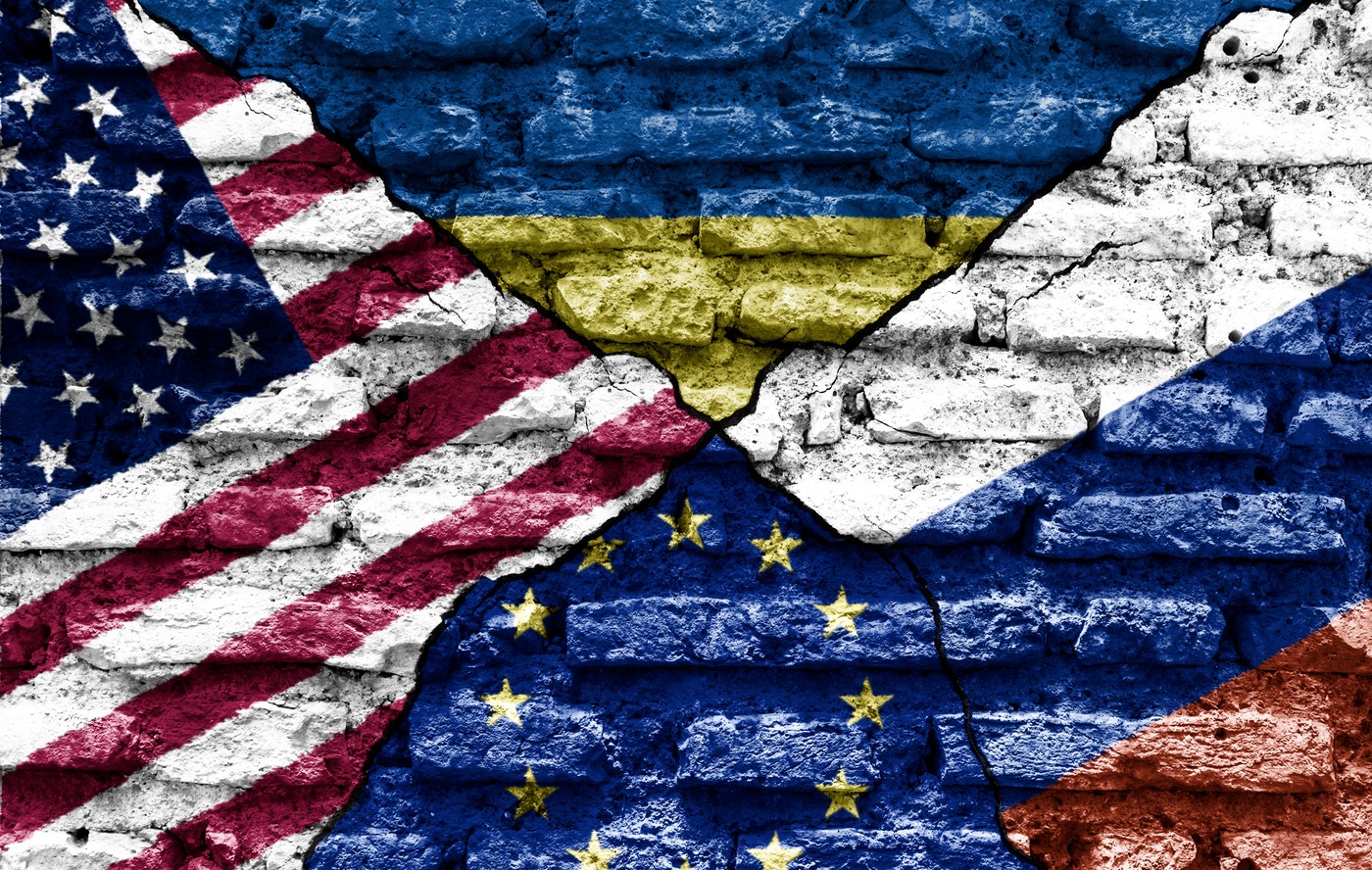 the flags of the USA, Ukraine, Europe and Russia painted on a ruined wall and divided by a diagonal crack.