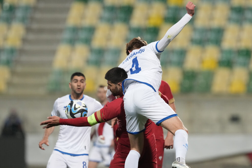 Aleksandar Mitrovic, background, and Cyprus' Hector Kyprianou challenge for the ball during an international friendly soccer match between Cyprus and Serbia at AEK arena stadium in Larnaca, Cyprus, Monday, March 25, 2024. (AP Photo/Petros Karadjias)