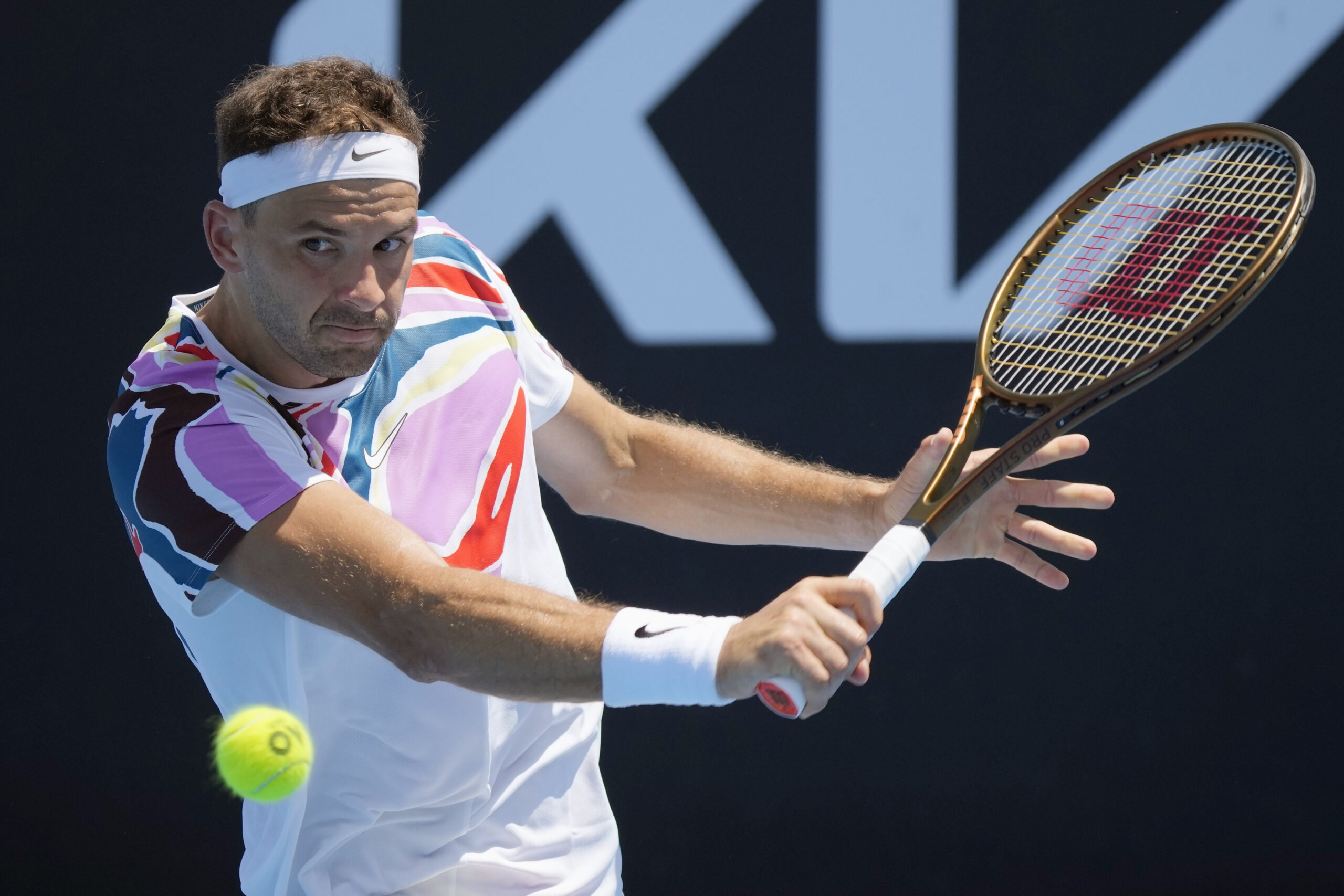 Grigor Dimitrov of Bulgaria plays a backhand return to Aslan Karatsev of Russia during their first round match at the Australian Open tennis championship in Melbourne, Australia, Tuesday, Jan. 17, 2023. (AP Photo/Dita Alangkara)