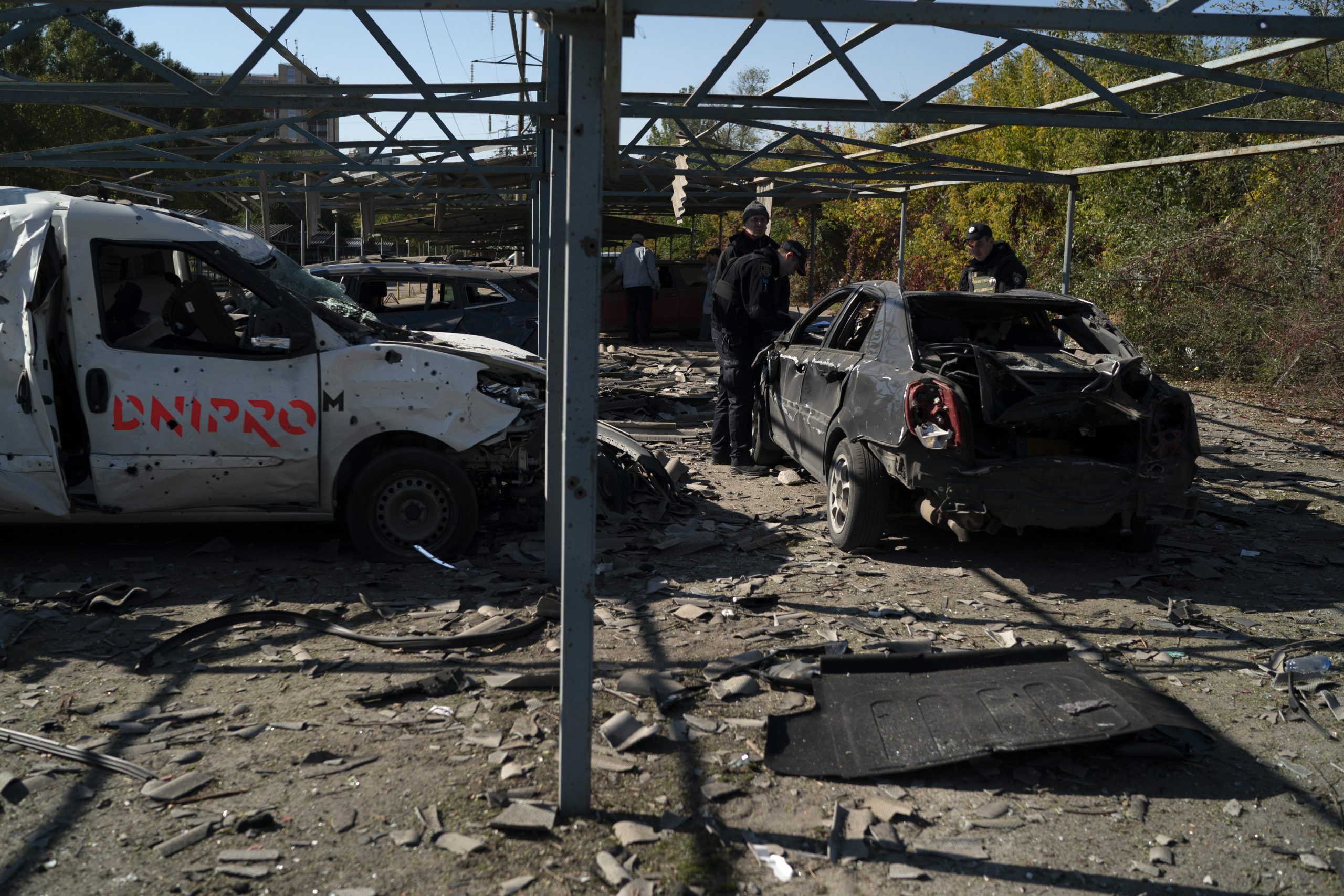 Police officers work at a site where several cars were damaged after a Russian attack in Zaporizhzhia, Ukraine, Saturday, Oct. 15, 2022. (AP Photo/Leo Correa)