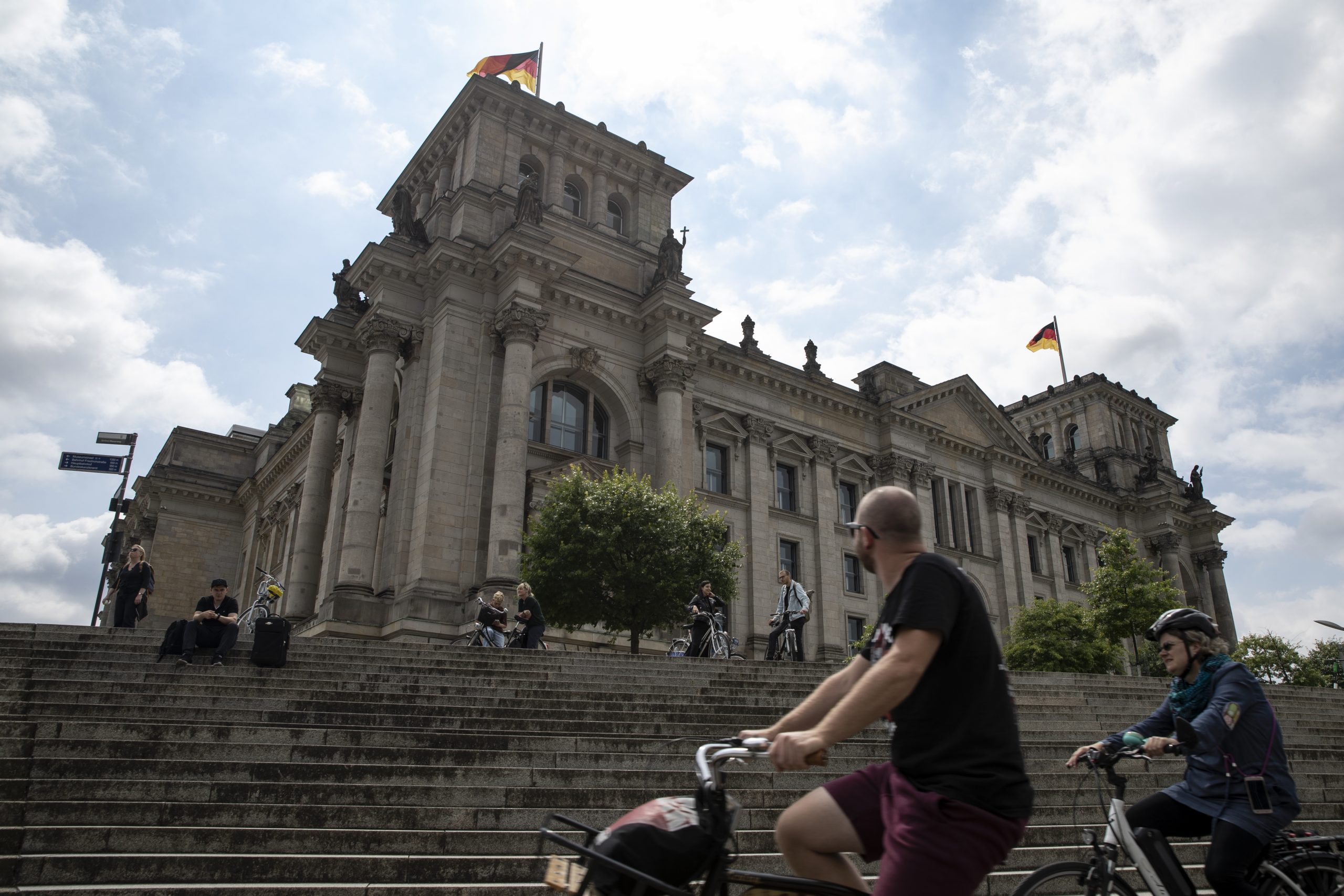 epa08552416 People ride on bicycles in front of the German parliament Bundestag in Berlin, Germany, 17 July 2020. The Reichstag building is one of the most favoured tourist attractions in the capital.  EPA-EFE/HAYOUNG JEON