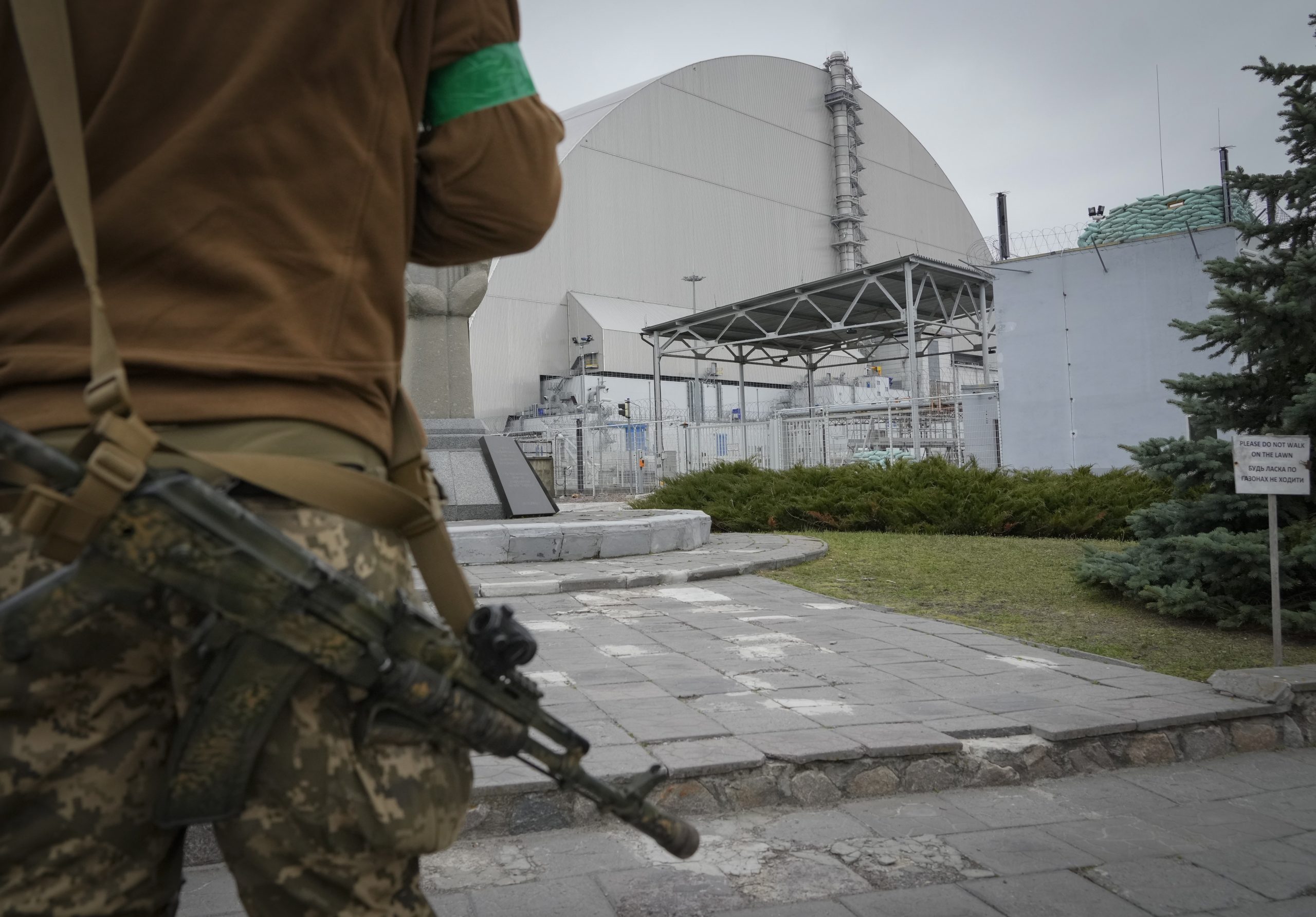 A Ukrainian soldier stands against the background of a shelter above the sarcophagus covering the exploded reactor at the Chernobyl nuclear power plant in Chernobyl, Ukraine, Saturday, April 16, 2022. (AP Photo/Efrem Lukatsky)