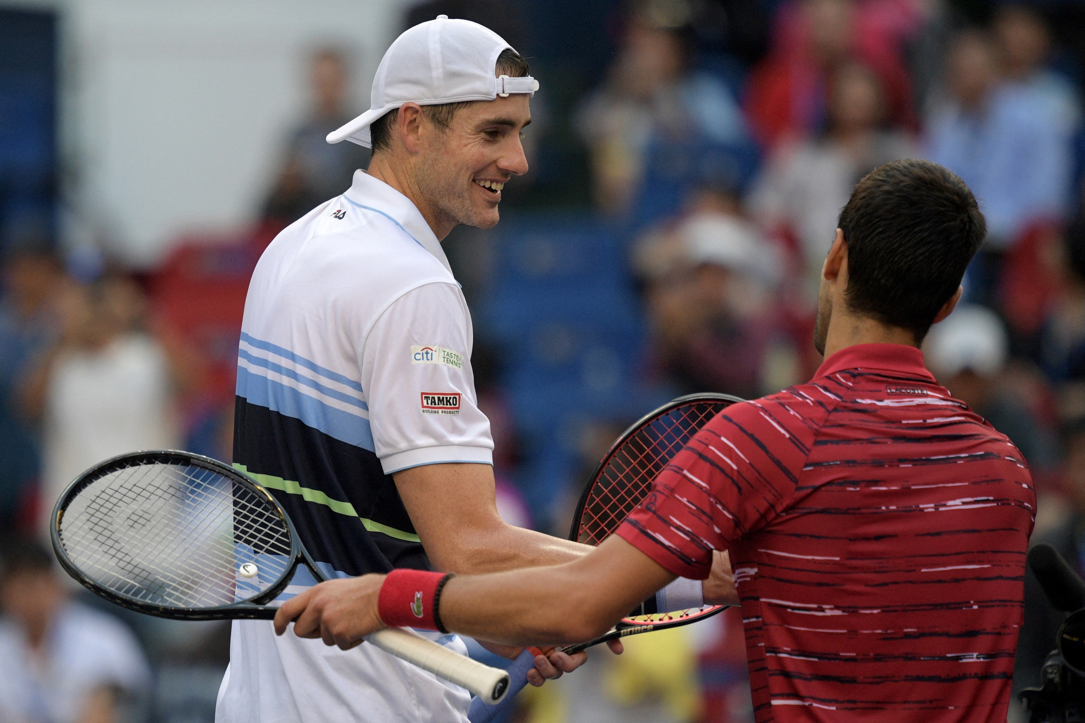 Novak Djokovic of Serbia (R) greets John Isner of the US