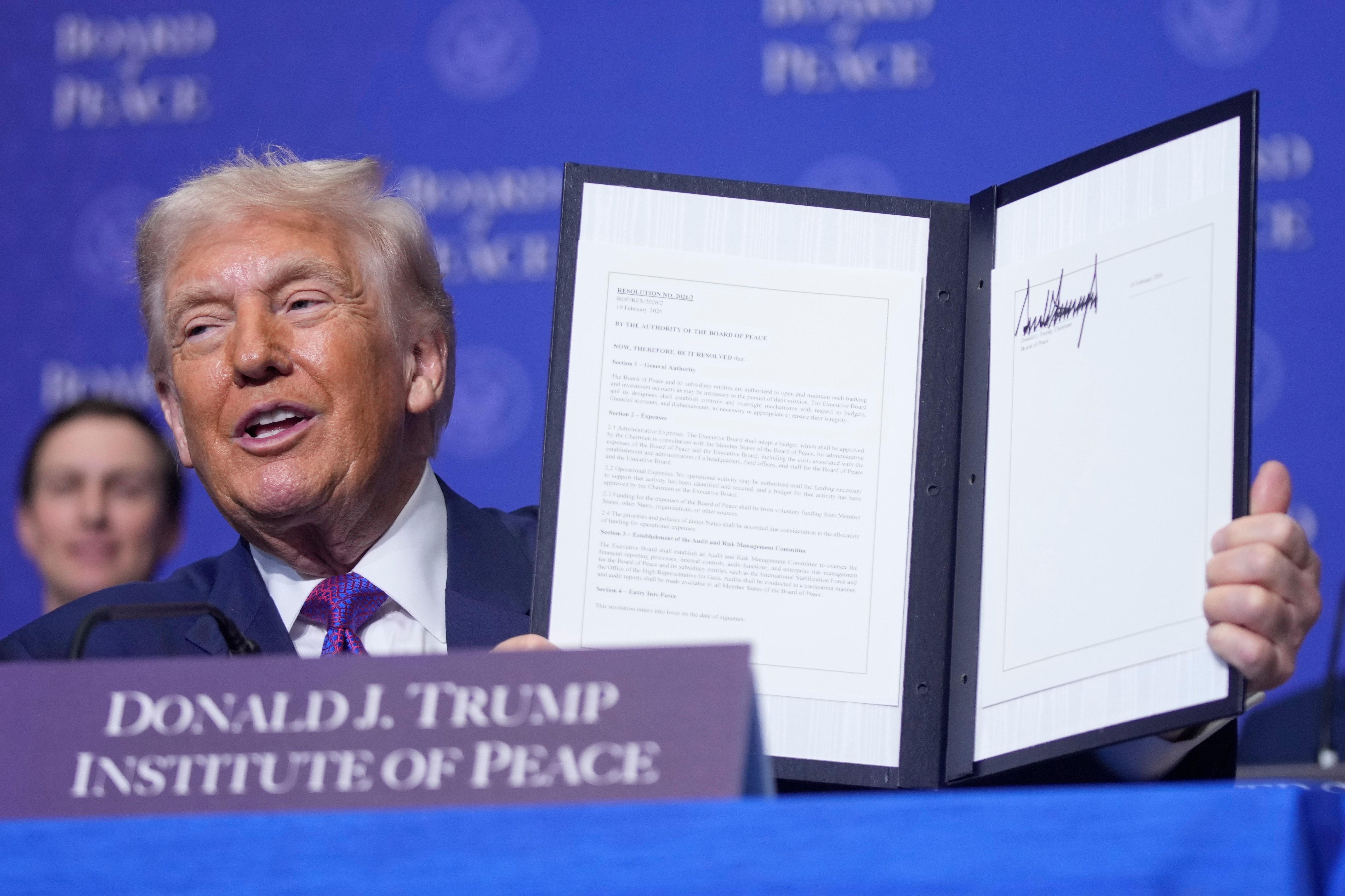 President Donald Trump holds up a signed resolution during a Board of Peace meeting at the U.S. Institute of Peace, Thursday, Feb. 19, 2026, in Washington. (AP Photo/Mark Schiefelbein)