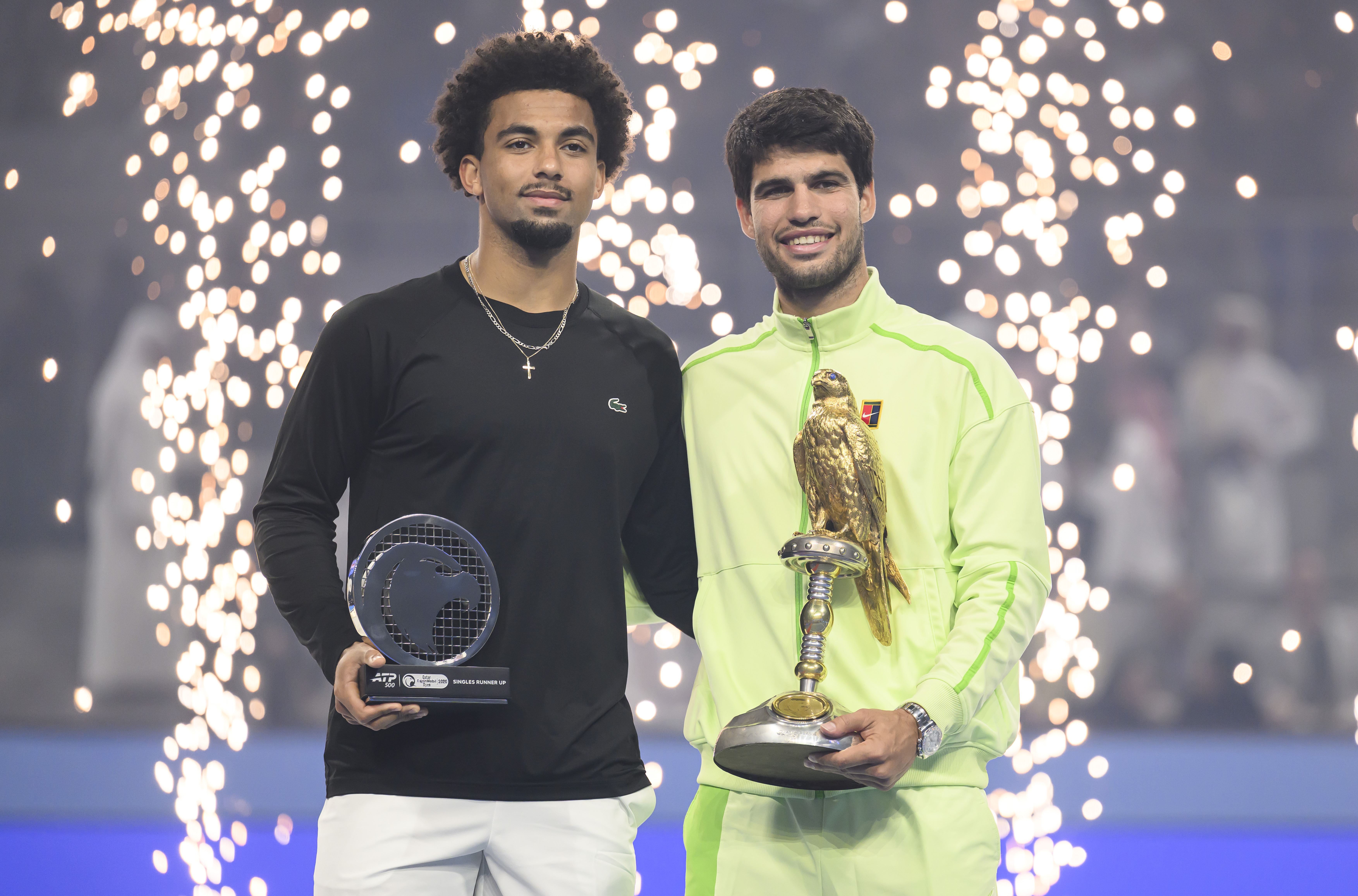 Champion Carlos Alcaraz (R) of Spain and runner-up Arthur Fils (L) of France with their trophies after the men's singles final match at the Qatar Open tennis tournament in Doha