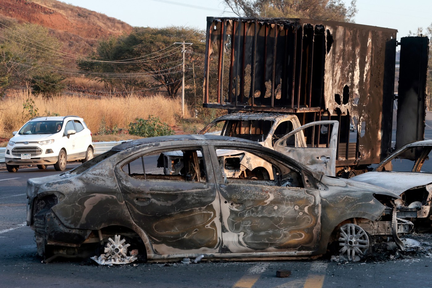 A view of burned cars and truck, allegedly set on fire by organised crime groups in response to an operation to arrest a high-priority security target, on a highway near Acatlan de Juarez, Jalisco state, Mexico on February 22, 2026.