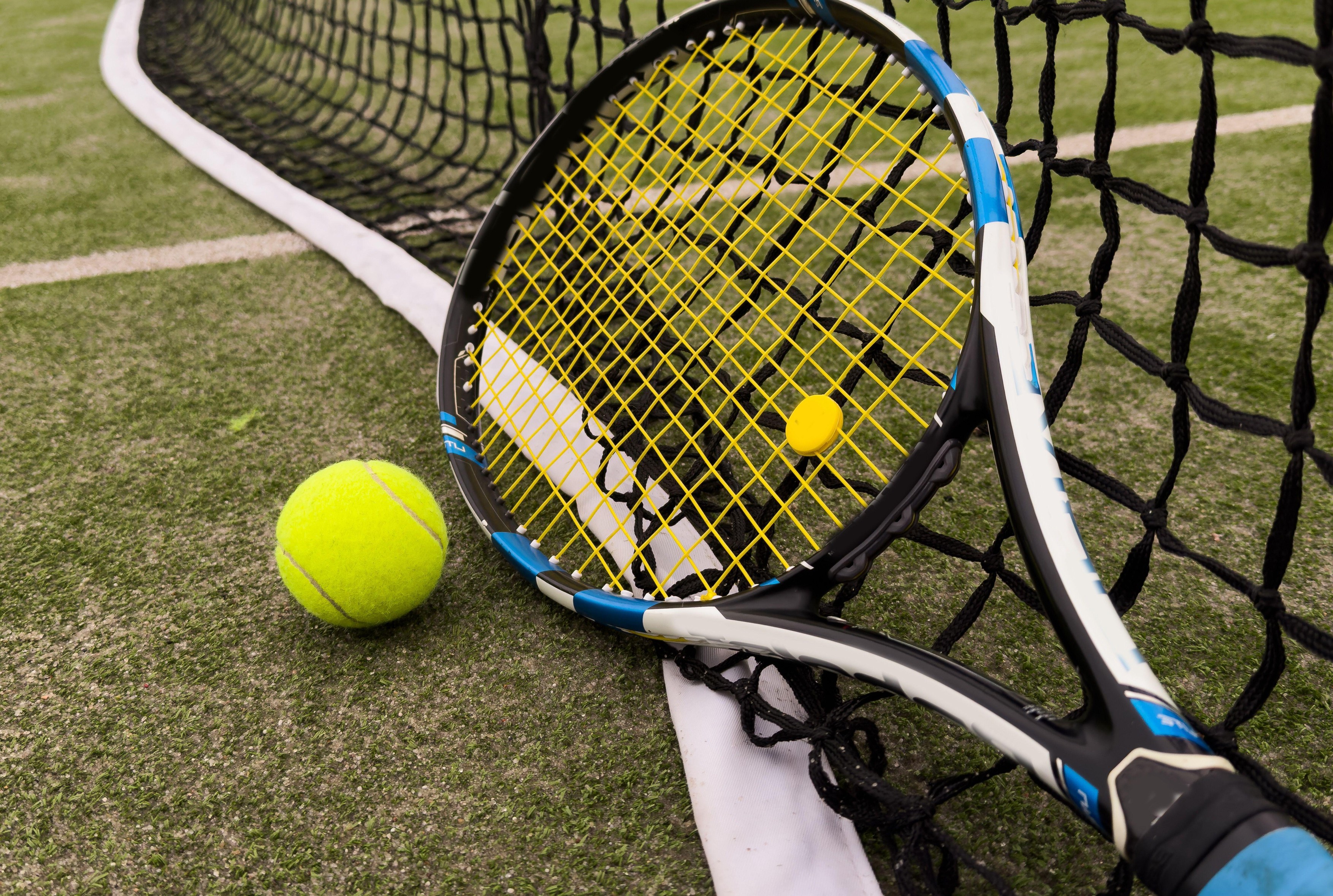 A tennis racket and new tennis ball on a tennis court