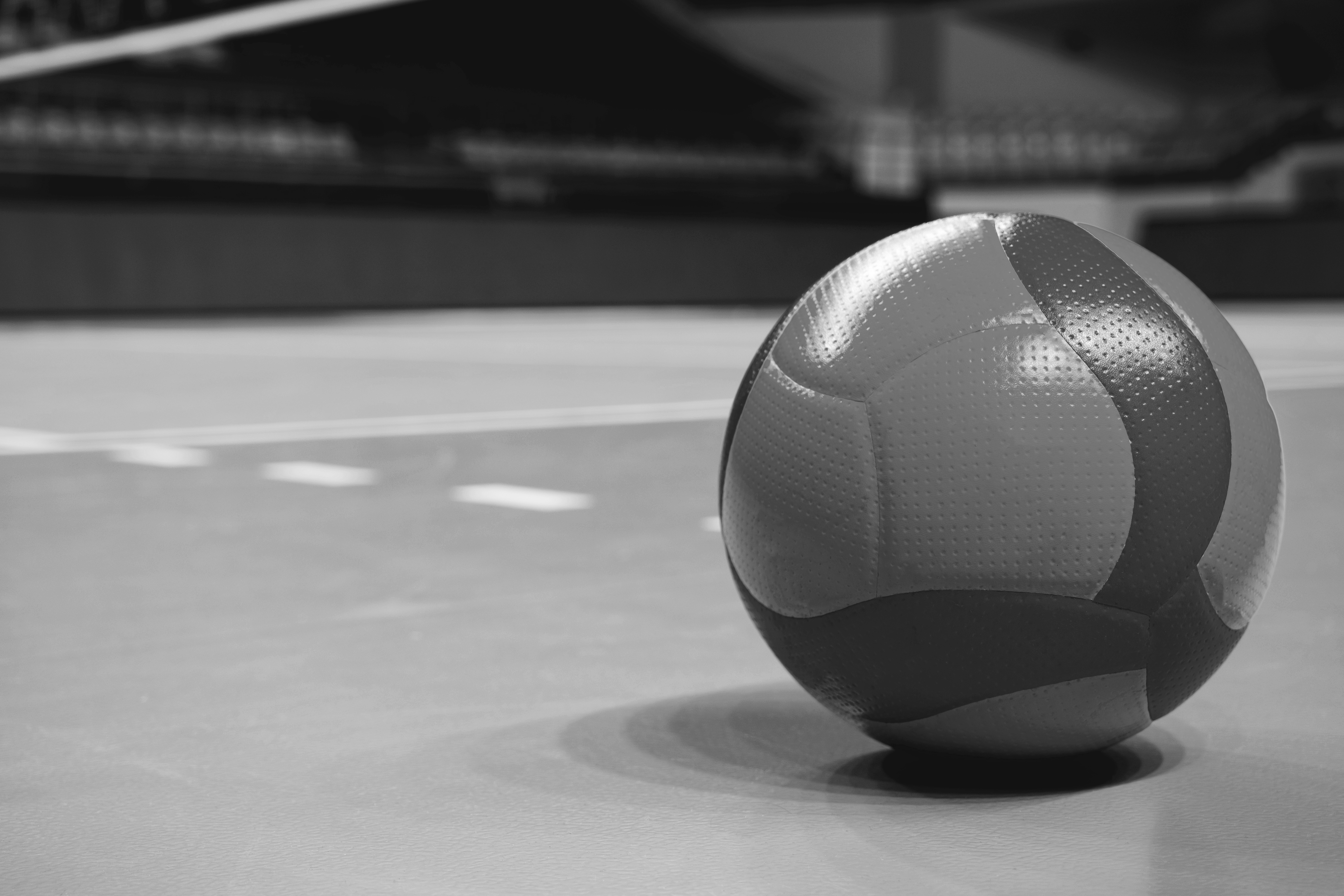 Volleyball ball on blurred wooden parquet background. Banner, space for text, close up view with details.