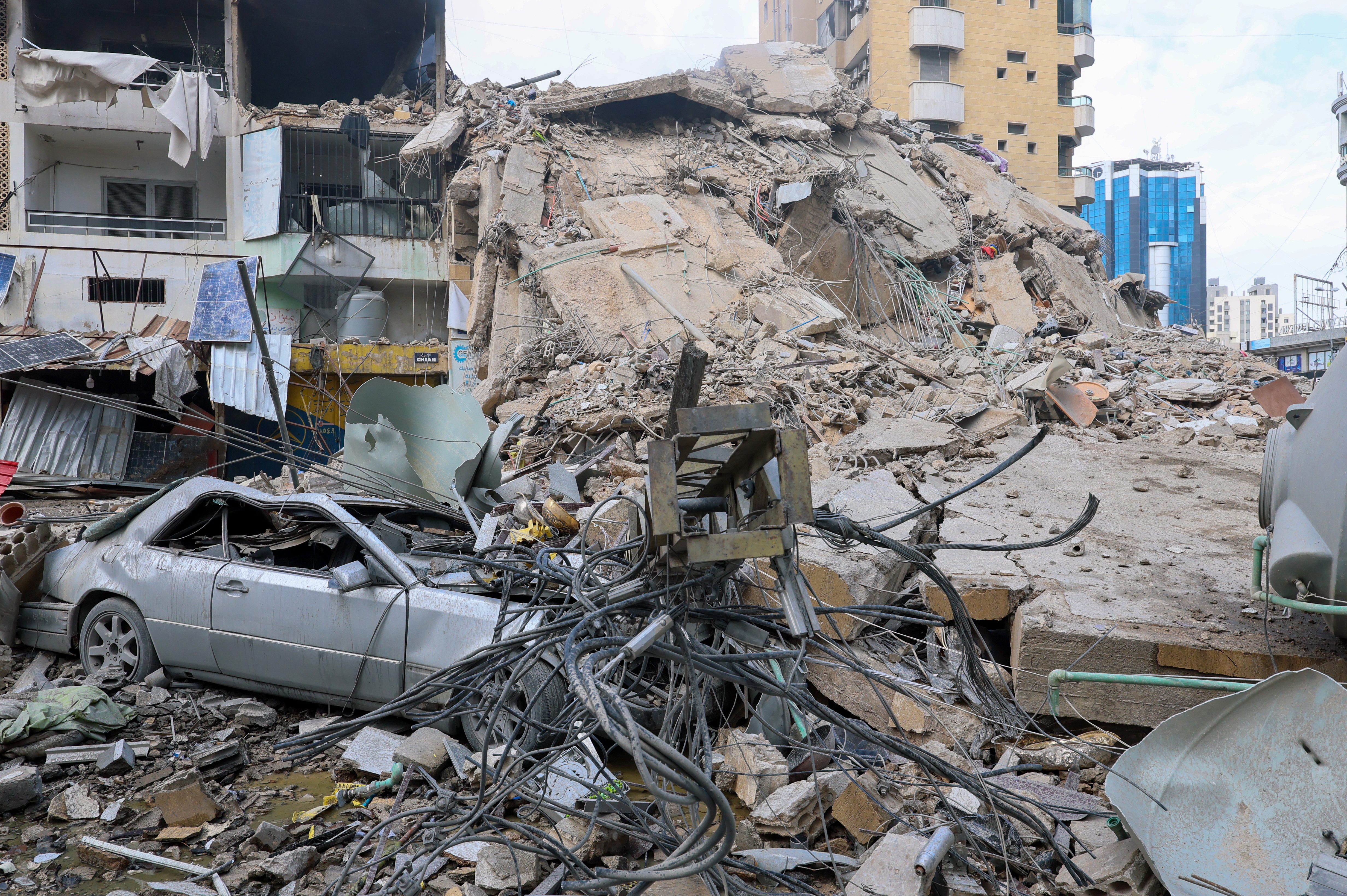epa12801160 A damaged car in front of a destroyed building following an Israeli air strike