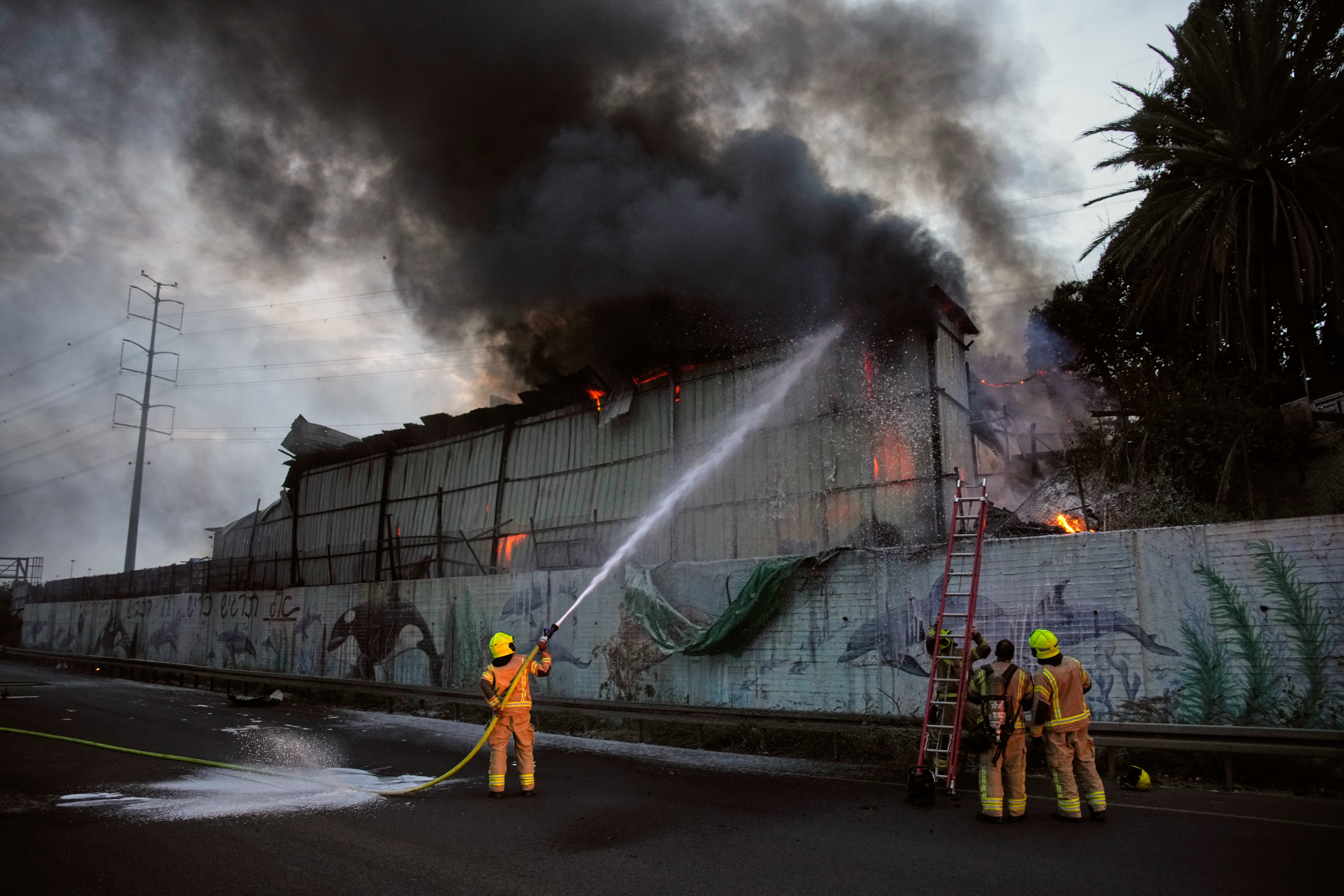 Firefighters try to extinguish flames at the site of a direct hit by an Iranian missile strike in Holon, central Israel, Friday, March 13, 2026. (AP Photo/Ohad Zwigenberg)
