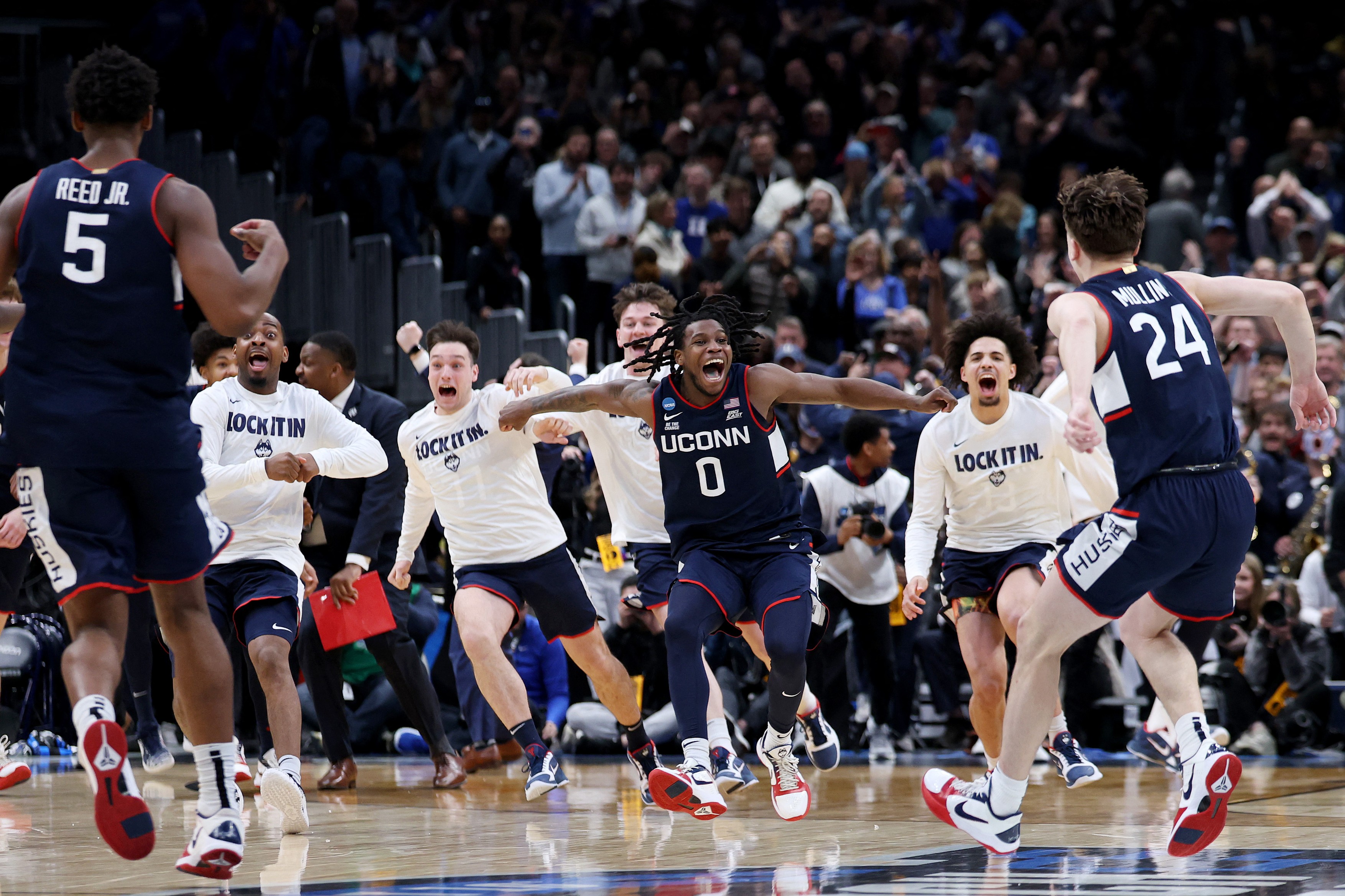 Braylon Mullins #24 celebrates with Malachi Smith #0 of the UConn Huskies after defeating the Duke Blue Devils 73-72 in the Elite Eight of the 2026 NCAA Men's Basketball Tournament at Capital One Arena