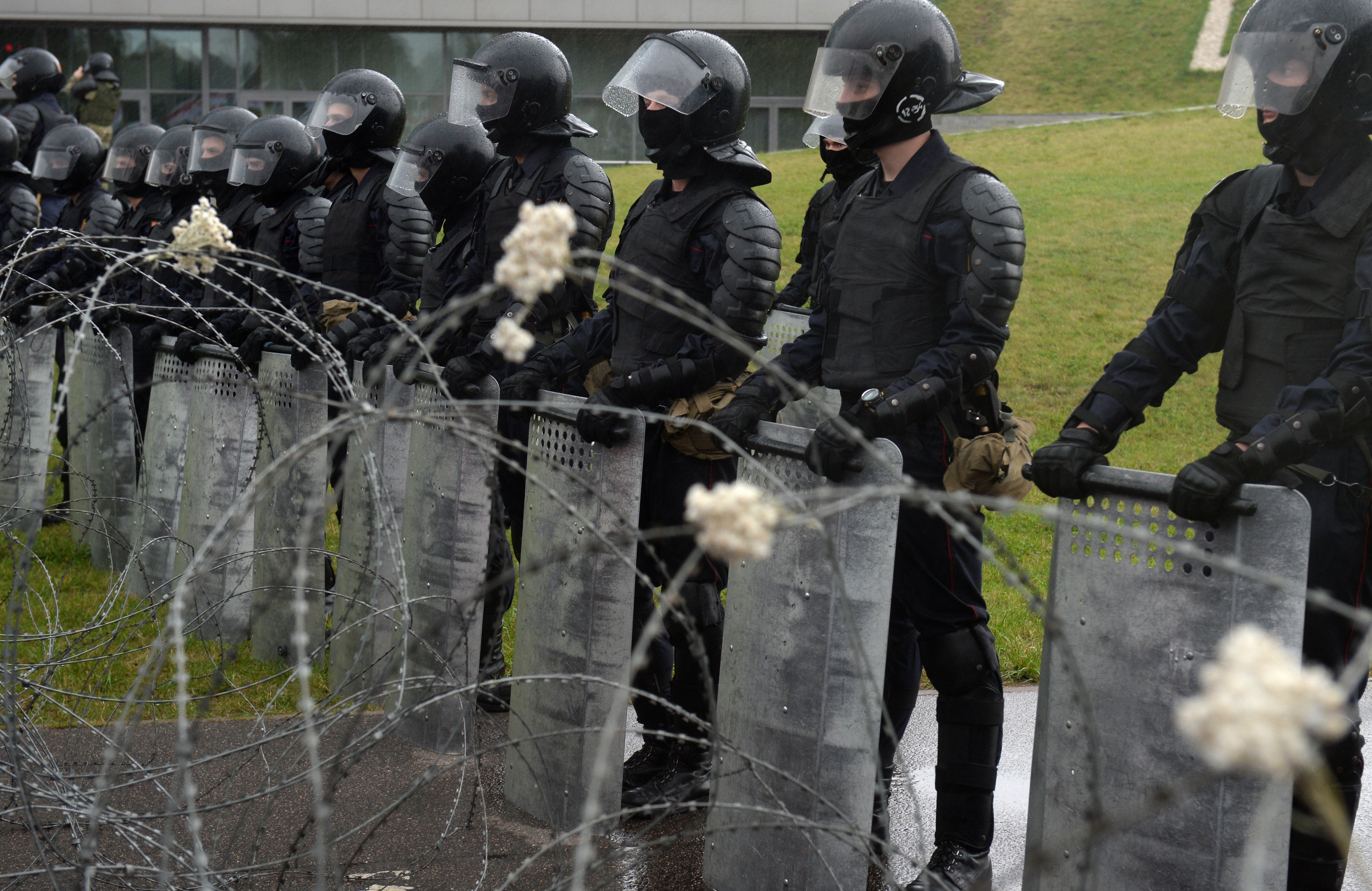 epa08651010 Belarusian Police stand behind a barbed wire as they block the road