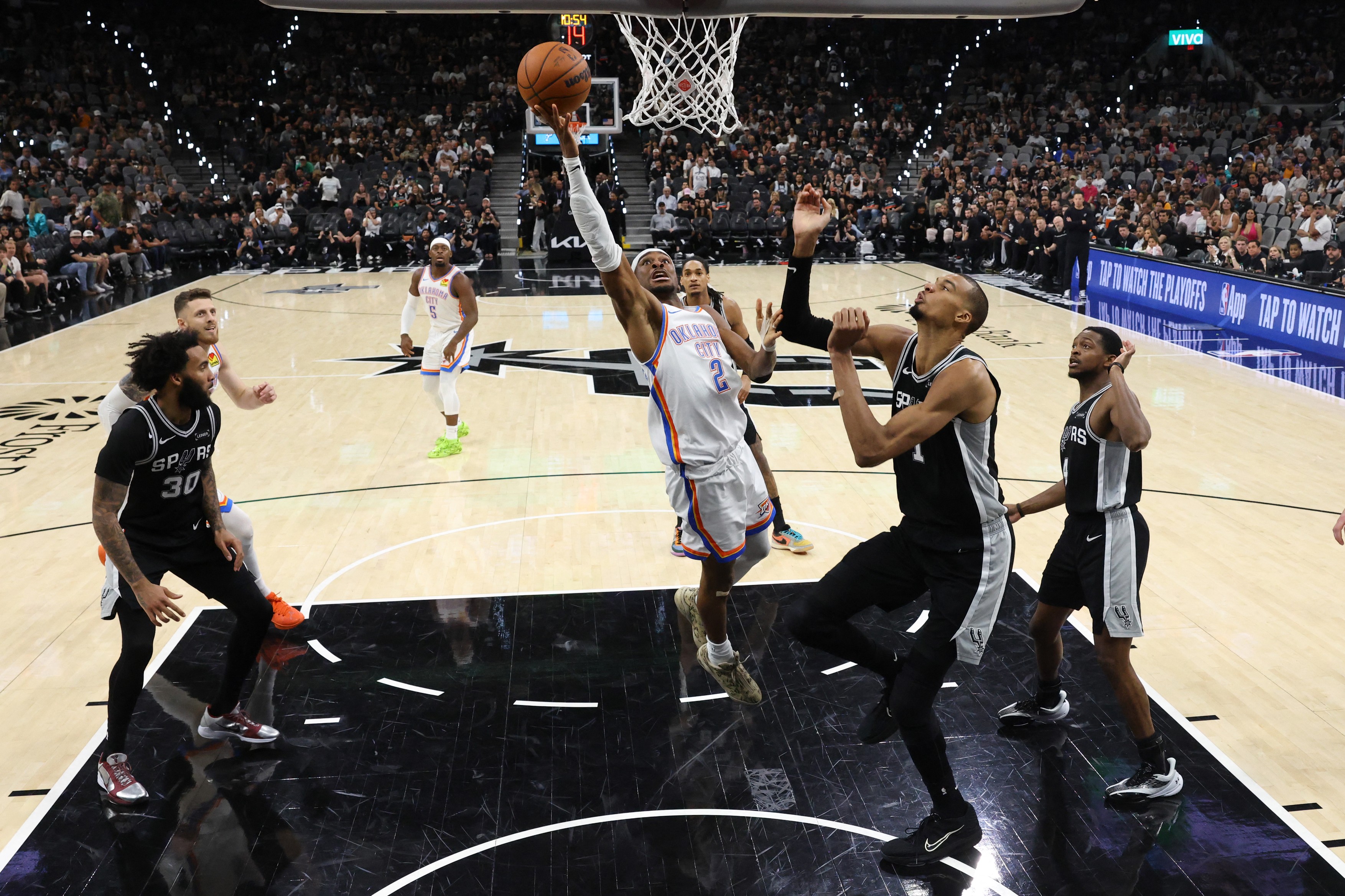Shai Gilgeous-Alexander #2 of the Oklahoma City Thunder shoots against Victor Wembanyama #1 of the San Antonio Spurs