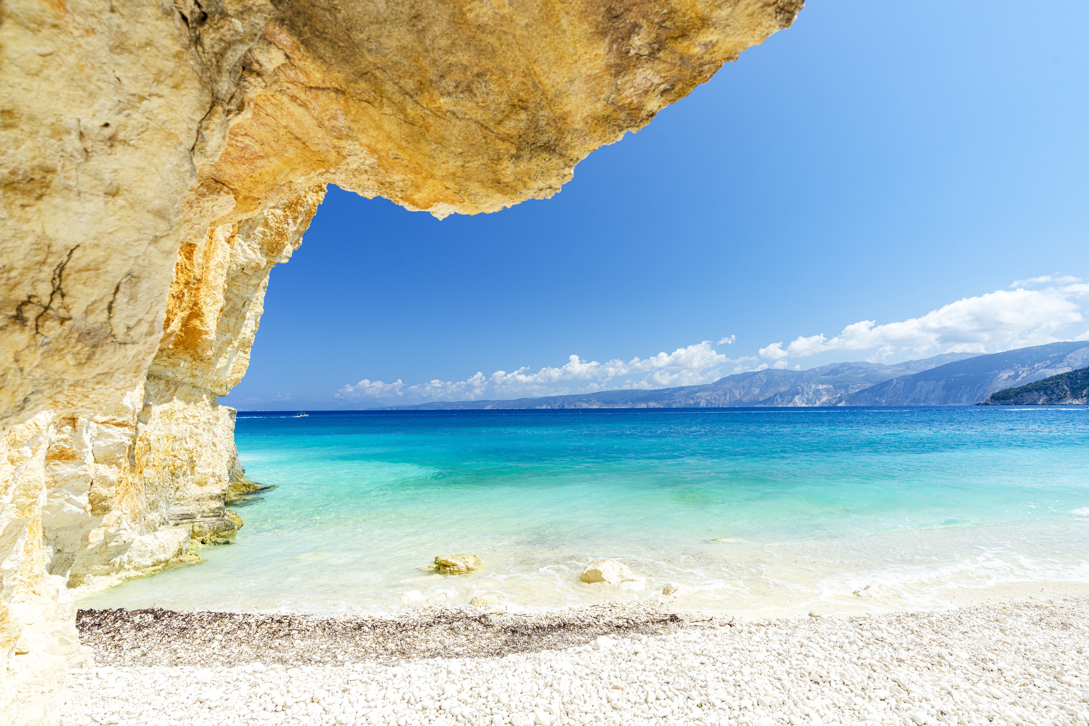 Crystal sea surrounded by limestone cliffs and white pebbles, Fteri Beach