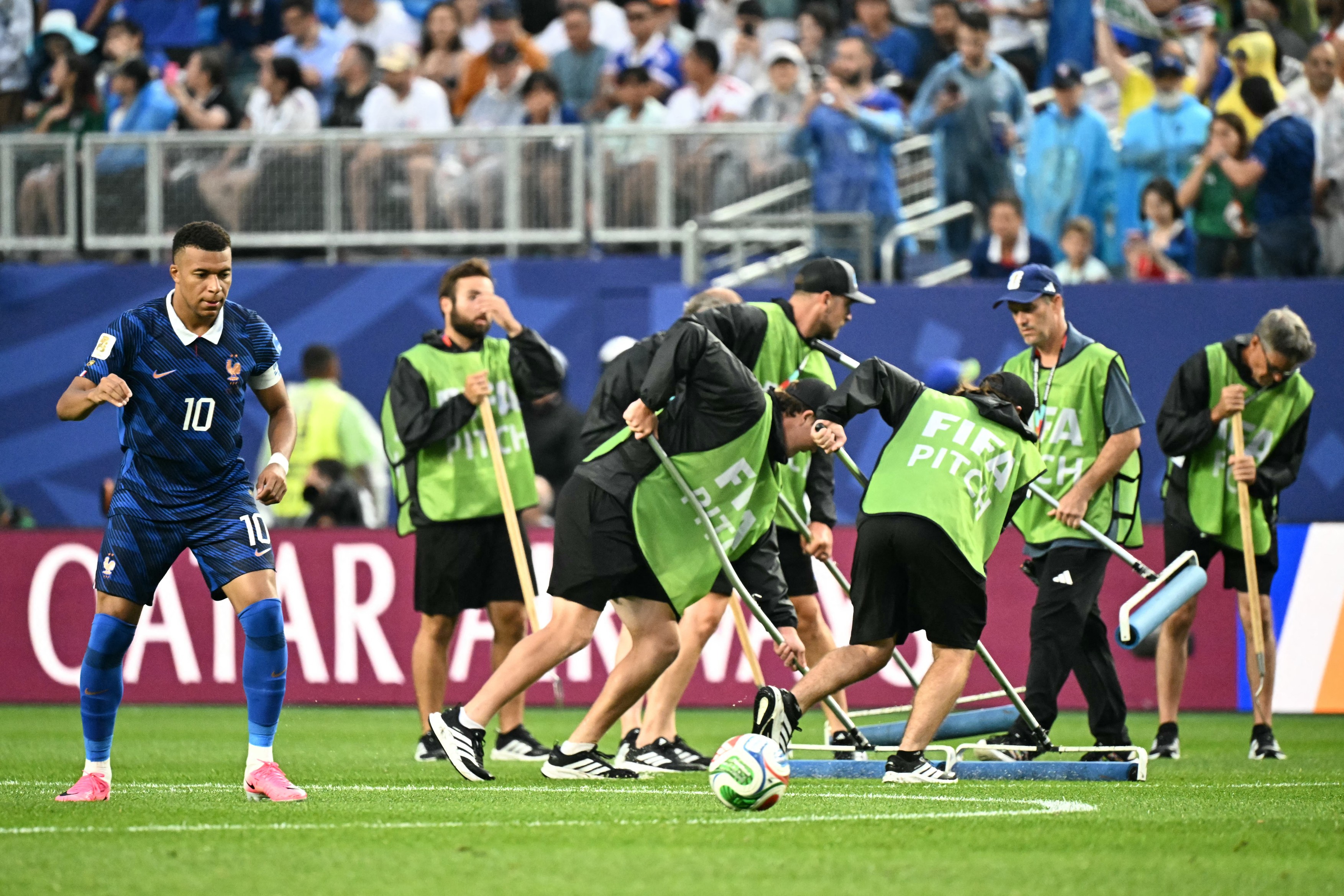 France's forward #10 Kylian Mbappe warms up next to staff workers
