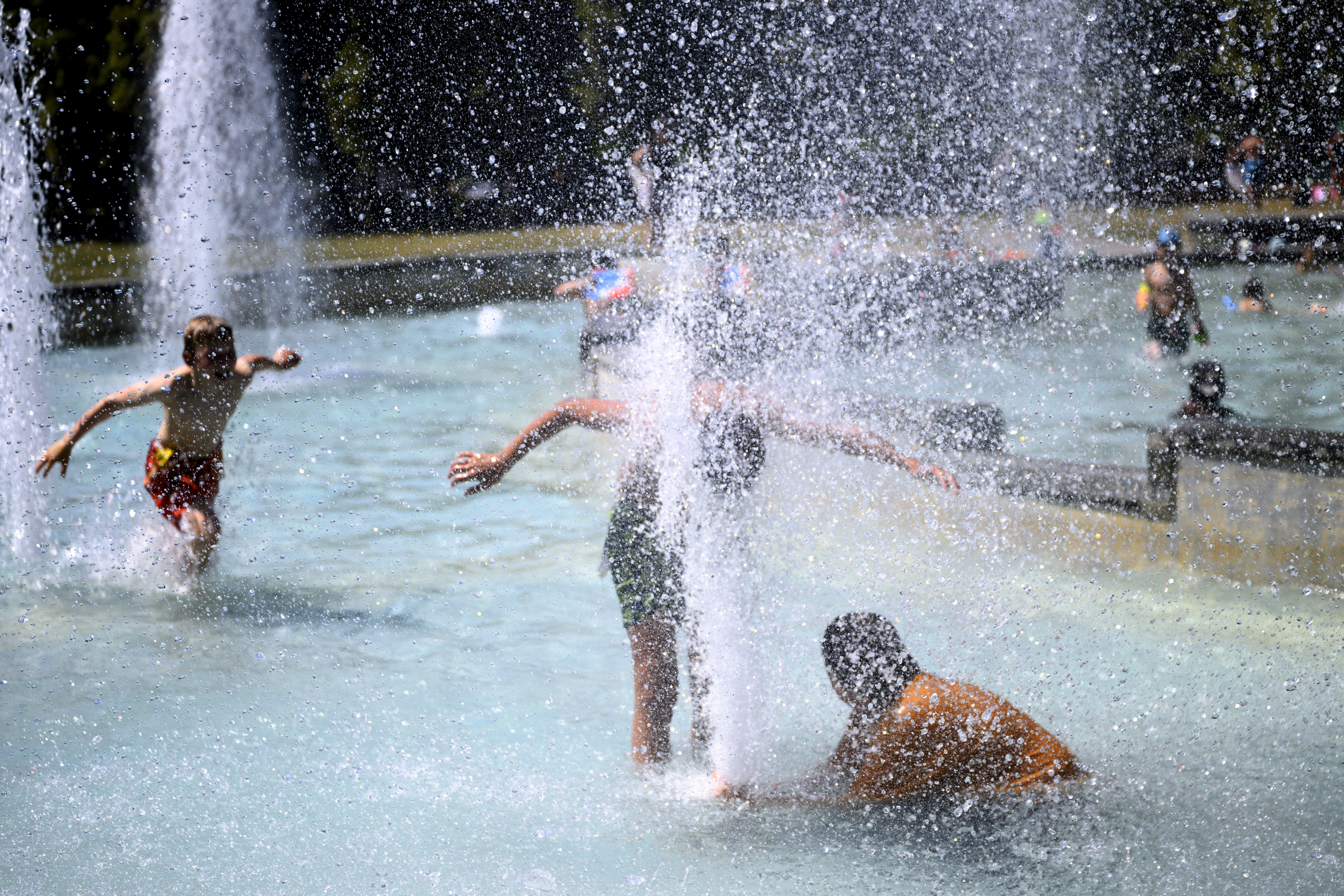 epa13058493 Children cool off by playing in the water of the public fountain in M