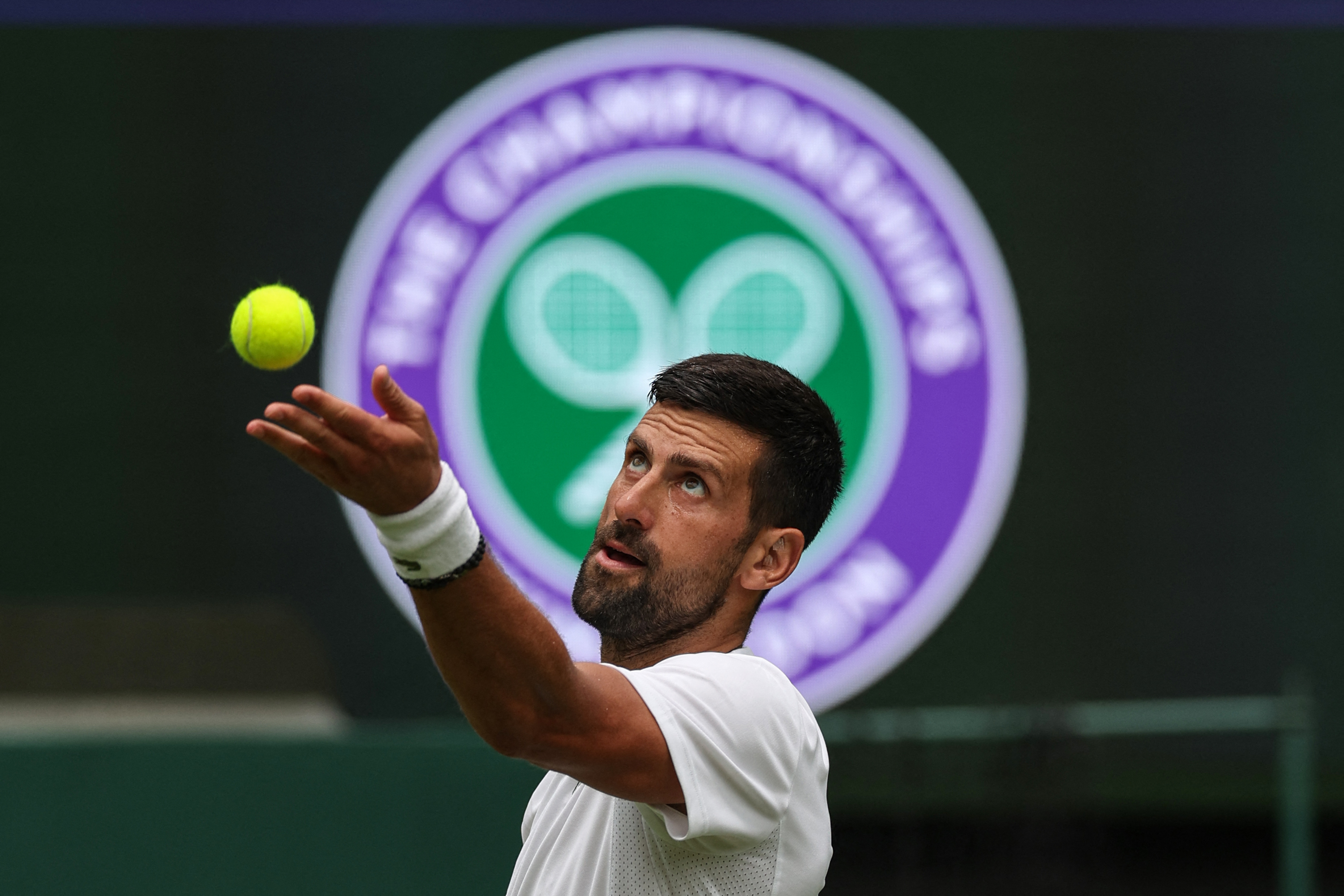 Serbia's Novak Djokovic serves as he practices with Italy's Jannik Sinner on No. 1 Court at The All England Lawn Tennis and Croquet Club in Wimbledon