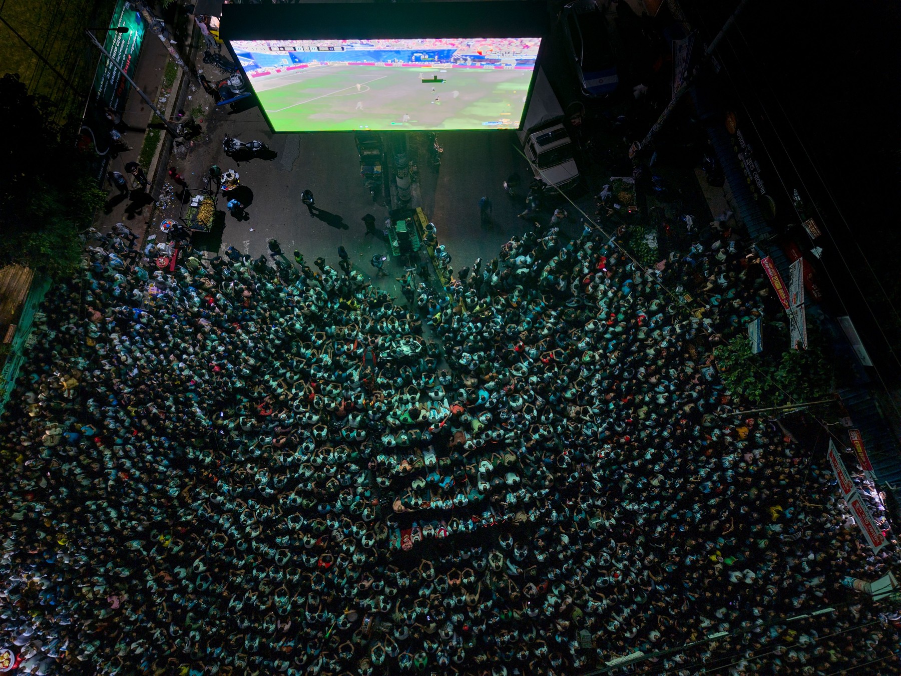 A top-down aerial drone shot captures thousands of football fans gathered in front