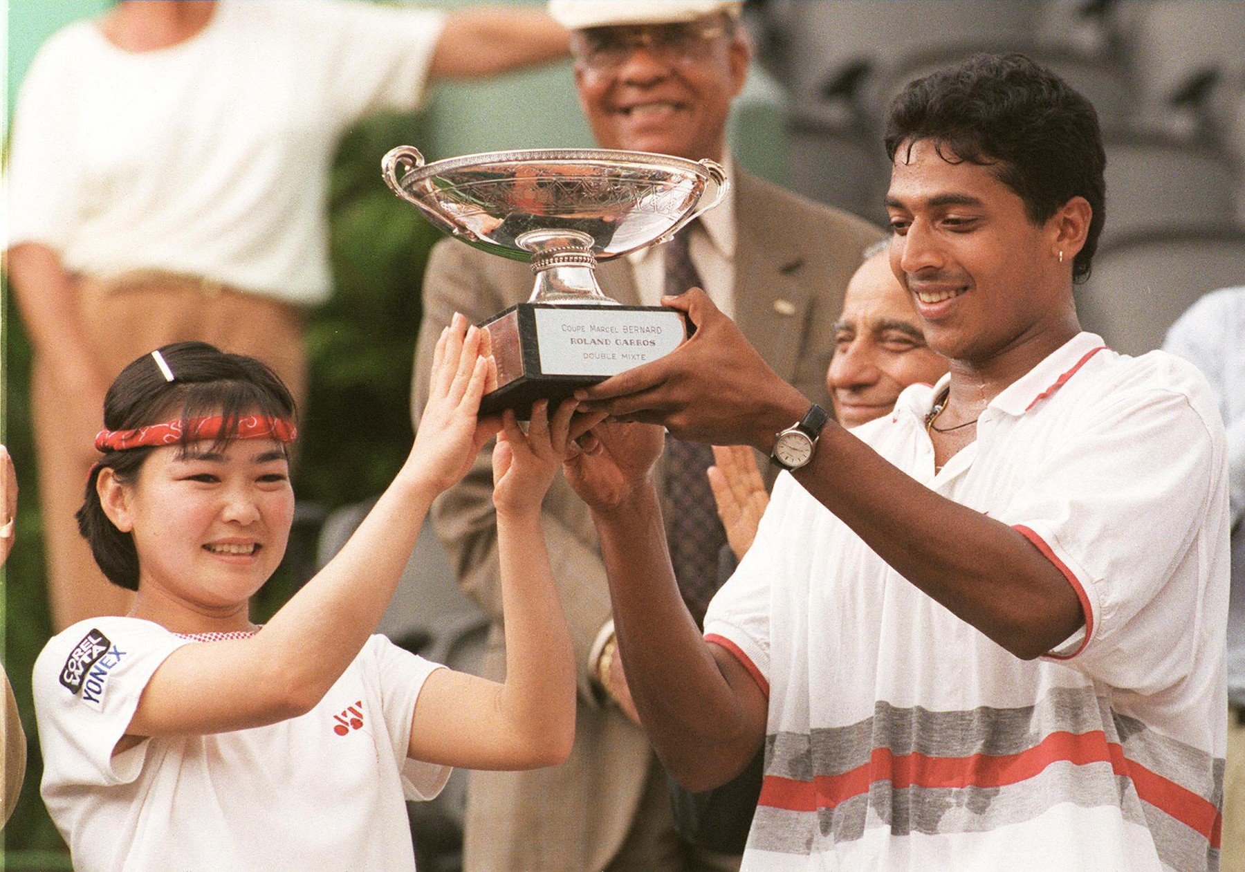 Rika Hiraki of Japan (L) and India's Mahesh Bhupathi hold the winners' trophy a