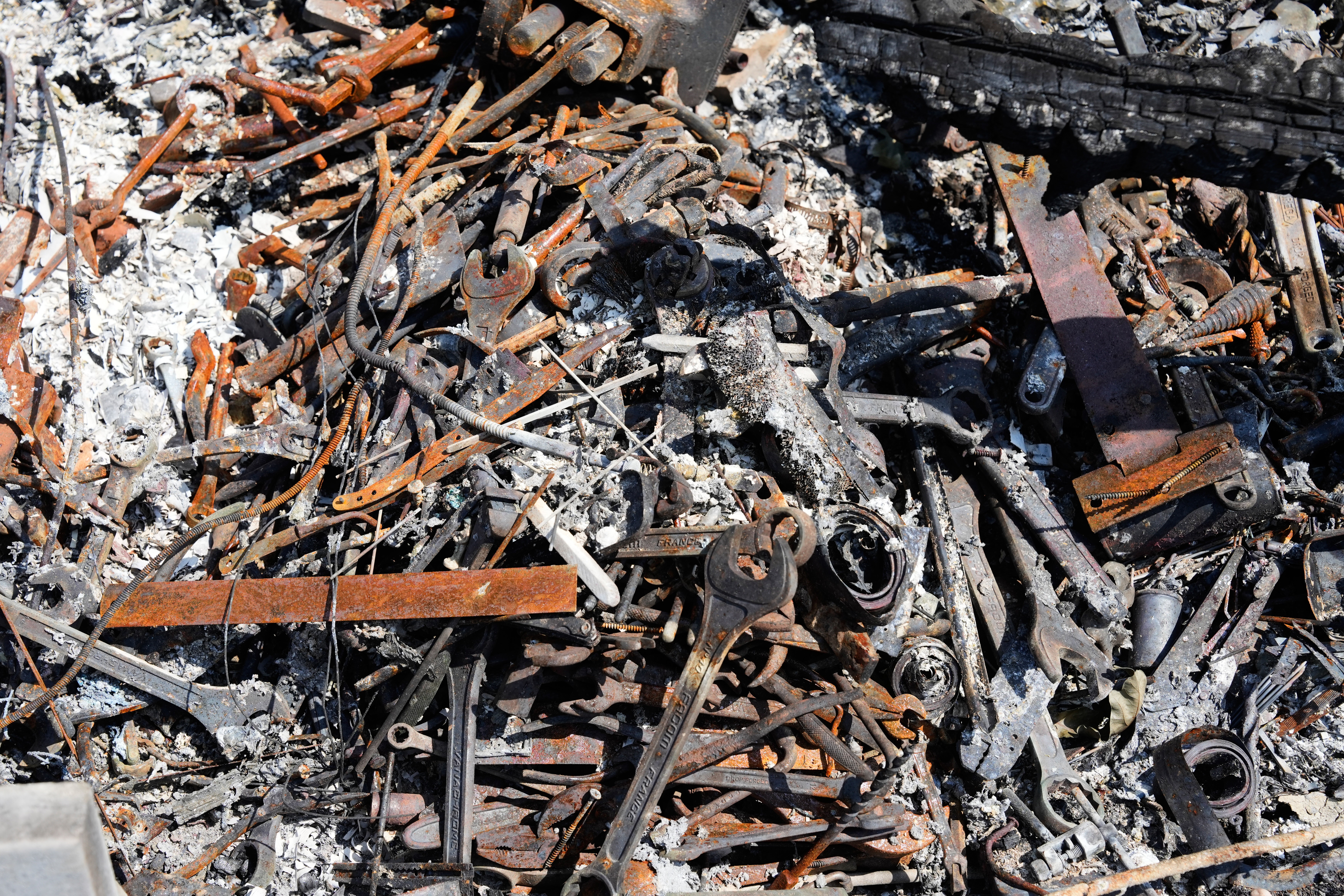 Burned tools and other items sit in a pile after wildfires raged in the village of Le Porge, on the Bay of Biscay, France, Monday, July 27, 2026. (AP Photo/Baz Ratner)