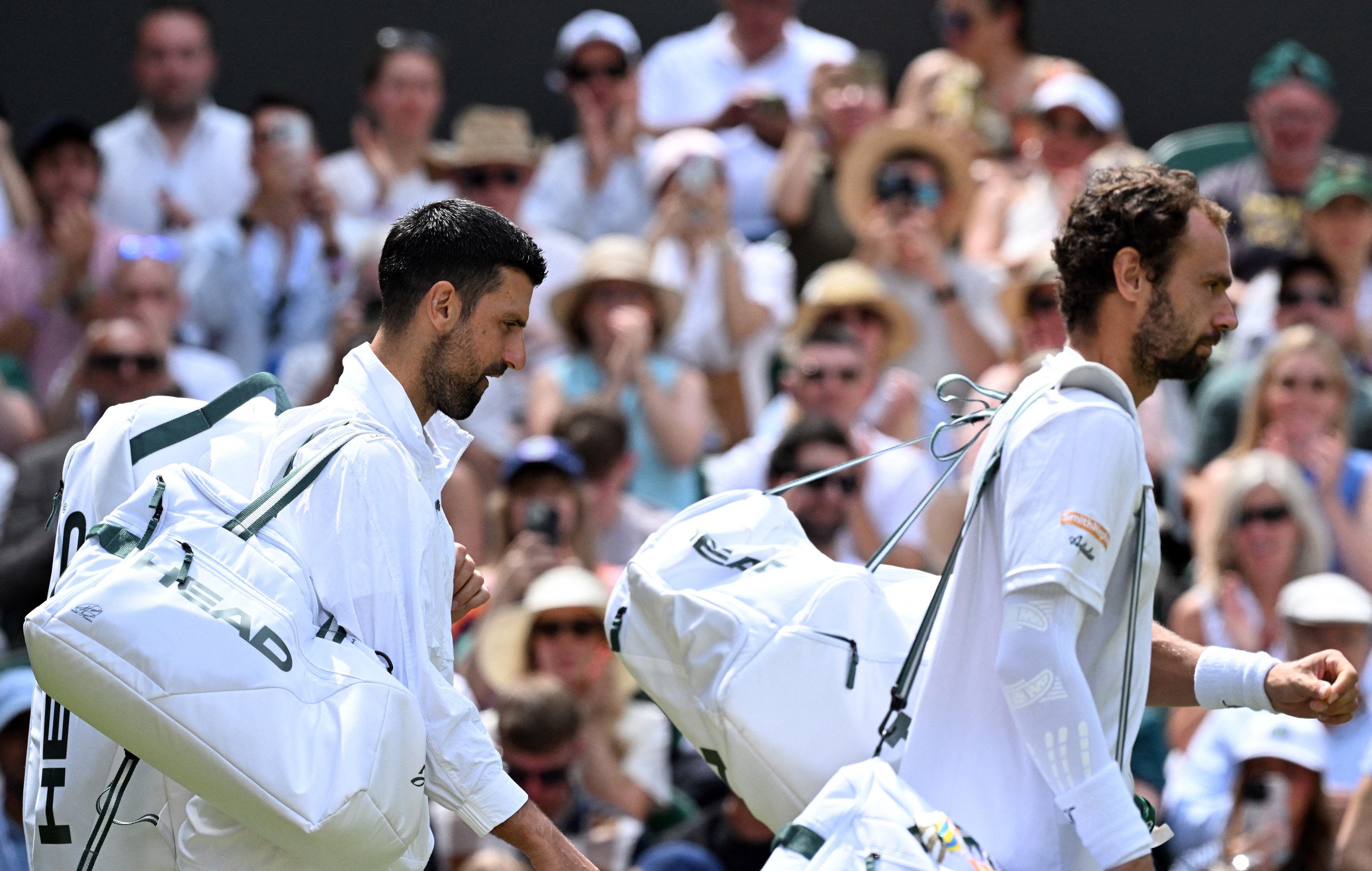 Serbia's Novak Djokovic (L) and Russia's Roman Safiullin arrive for their men's singles round of 16 tennis match on the seventh day of the 2026 Wimbledon Championships