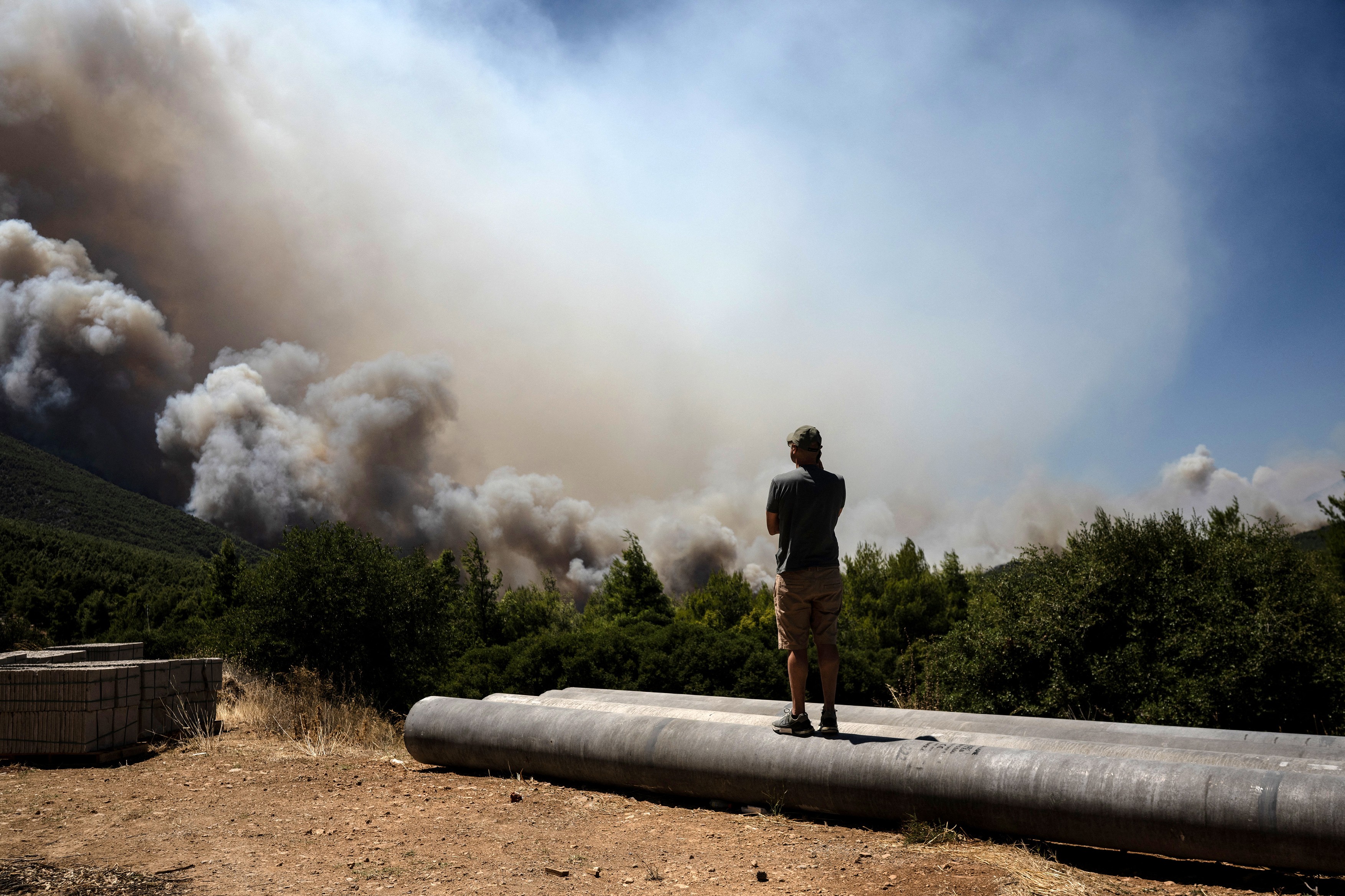 A local resident watches heavy smoke rising from a wildfire in the area of Porto Germeno,