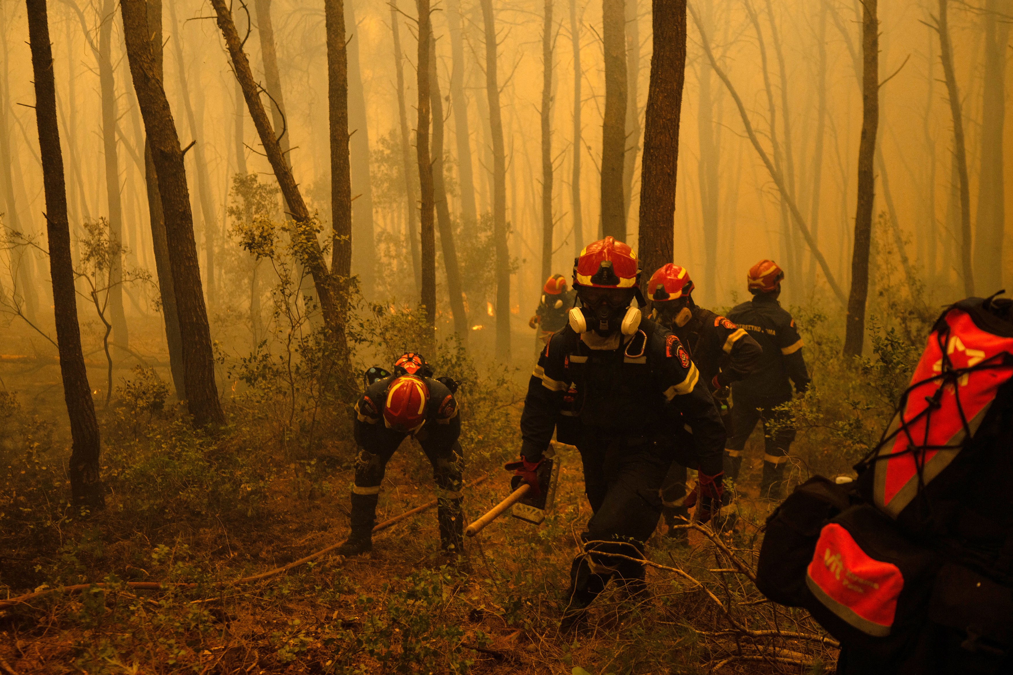 Greek firefighters try to extinguish a wildfire in the area of Porto Germeno,