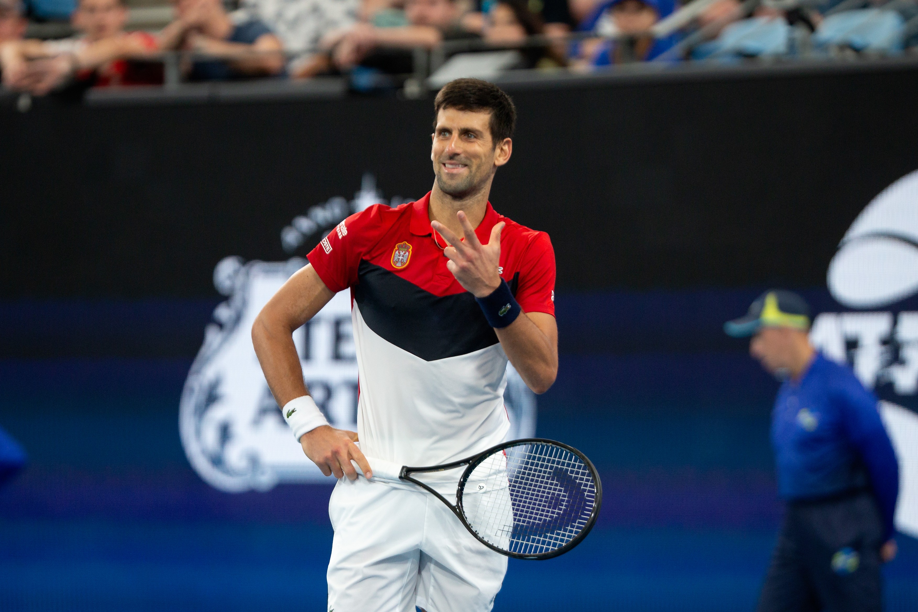 Novak Djokovic of Serbia smiles and holds up three fingers